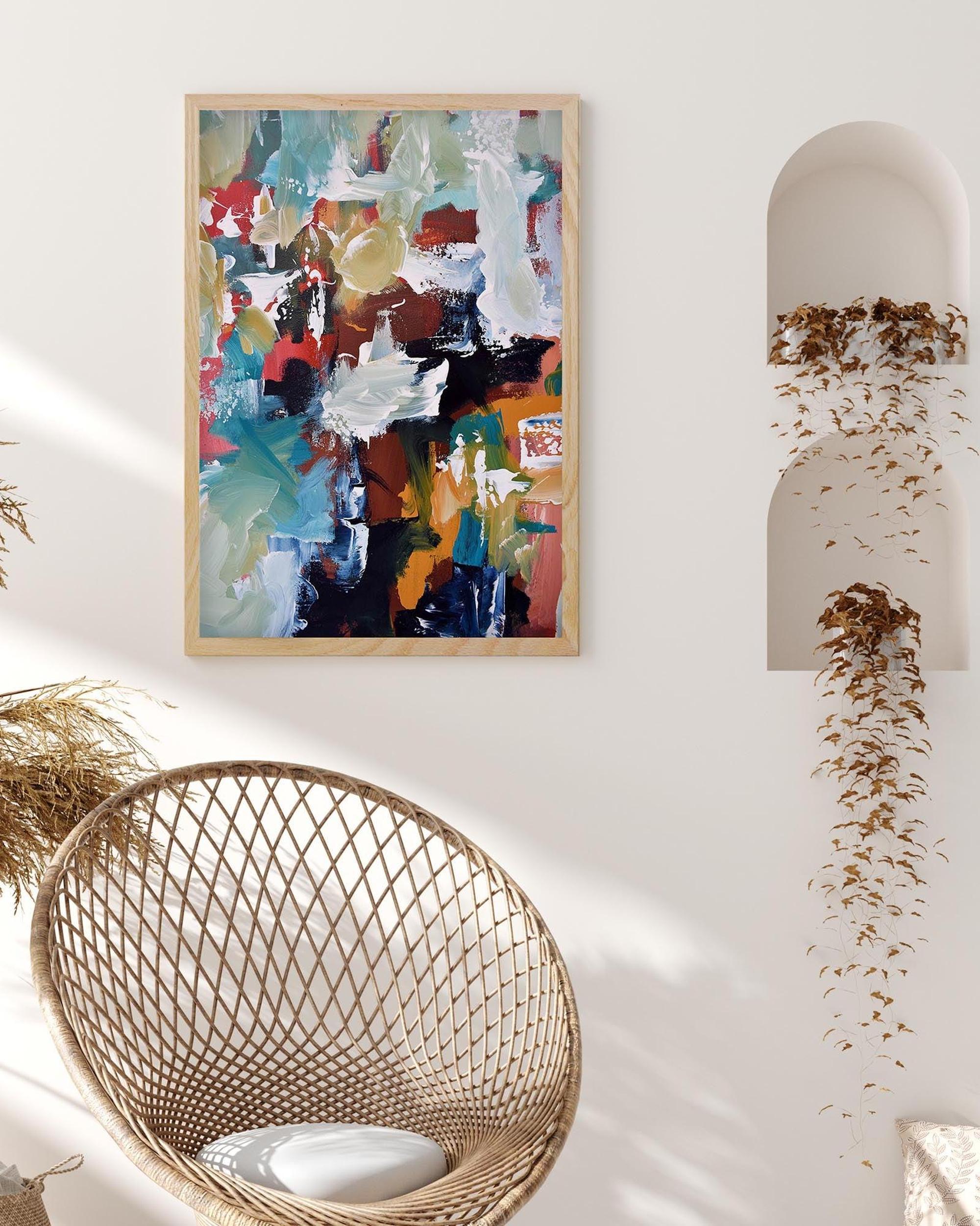 Abstract painting on a wall above a wicker chair with a white cushion.
