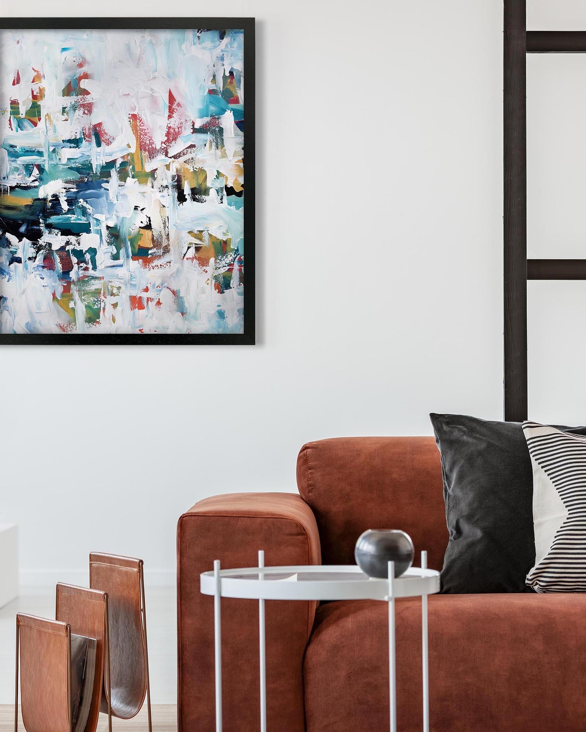 Modern living room with a brown sofa, abstract painting, and decorative items.
