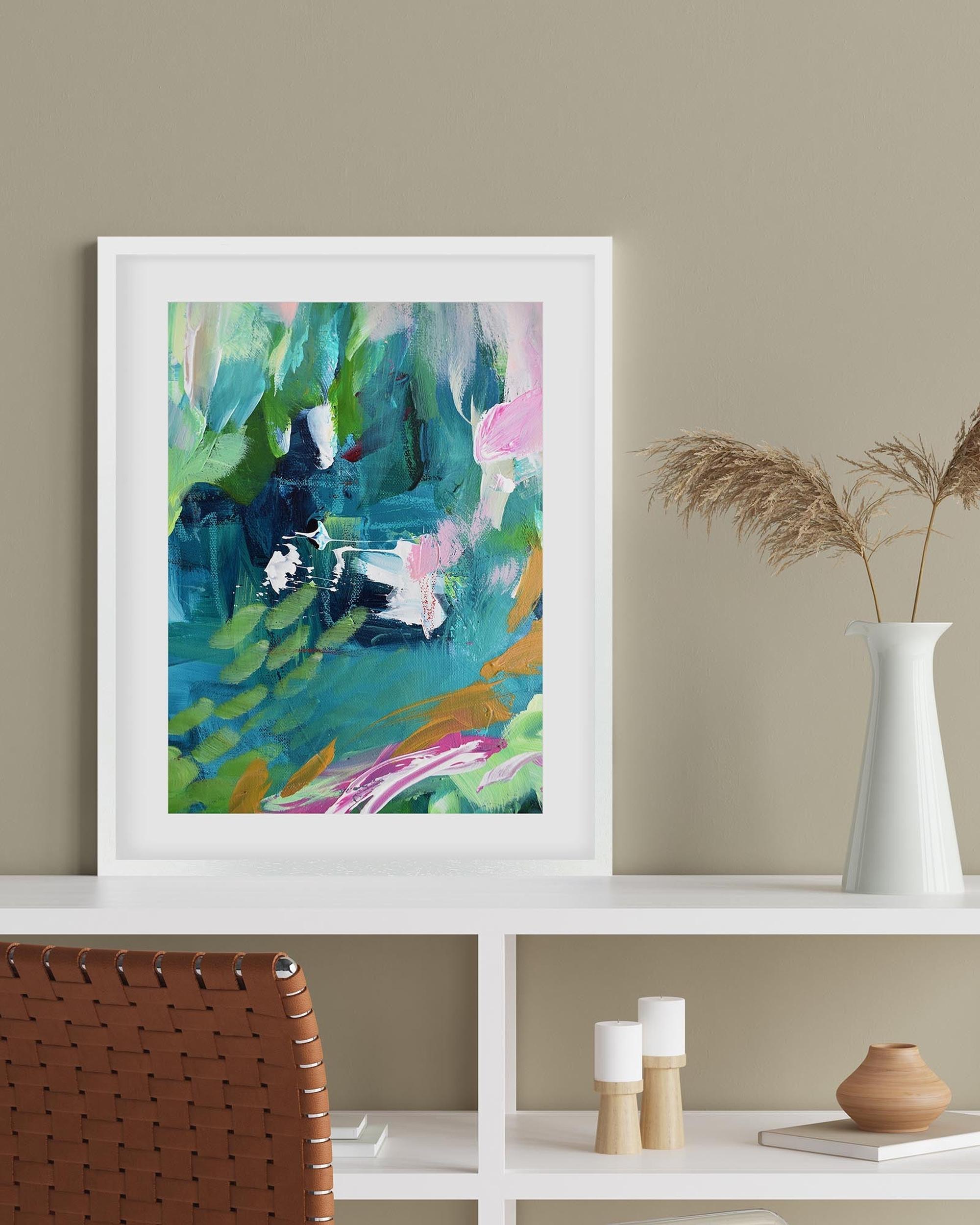 Framed abstract painting on a wall above a white shelf with decorative items.
