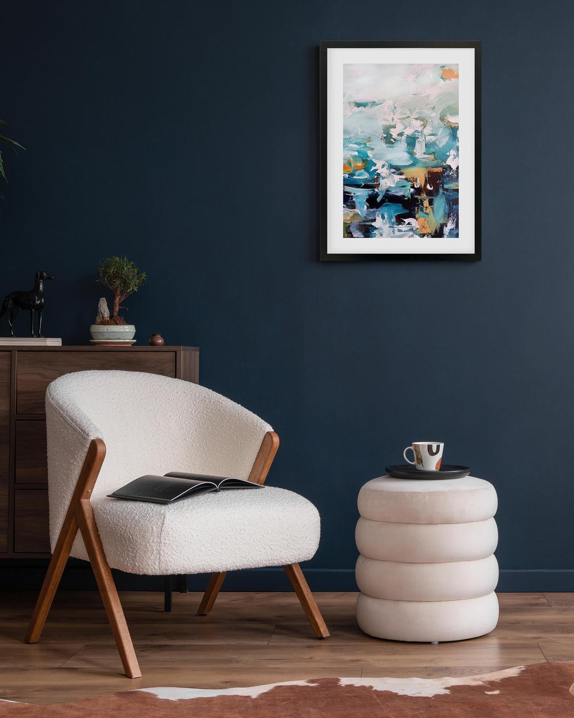 Modern living room with a white armchair, side table, and abstract painting on a dark blue wall.
