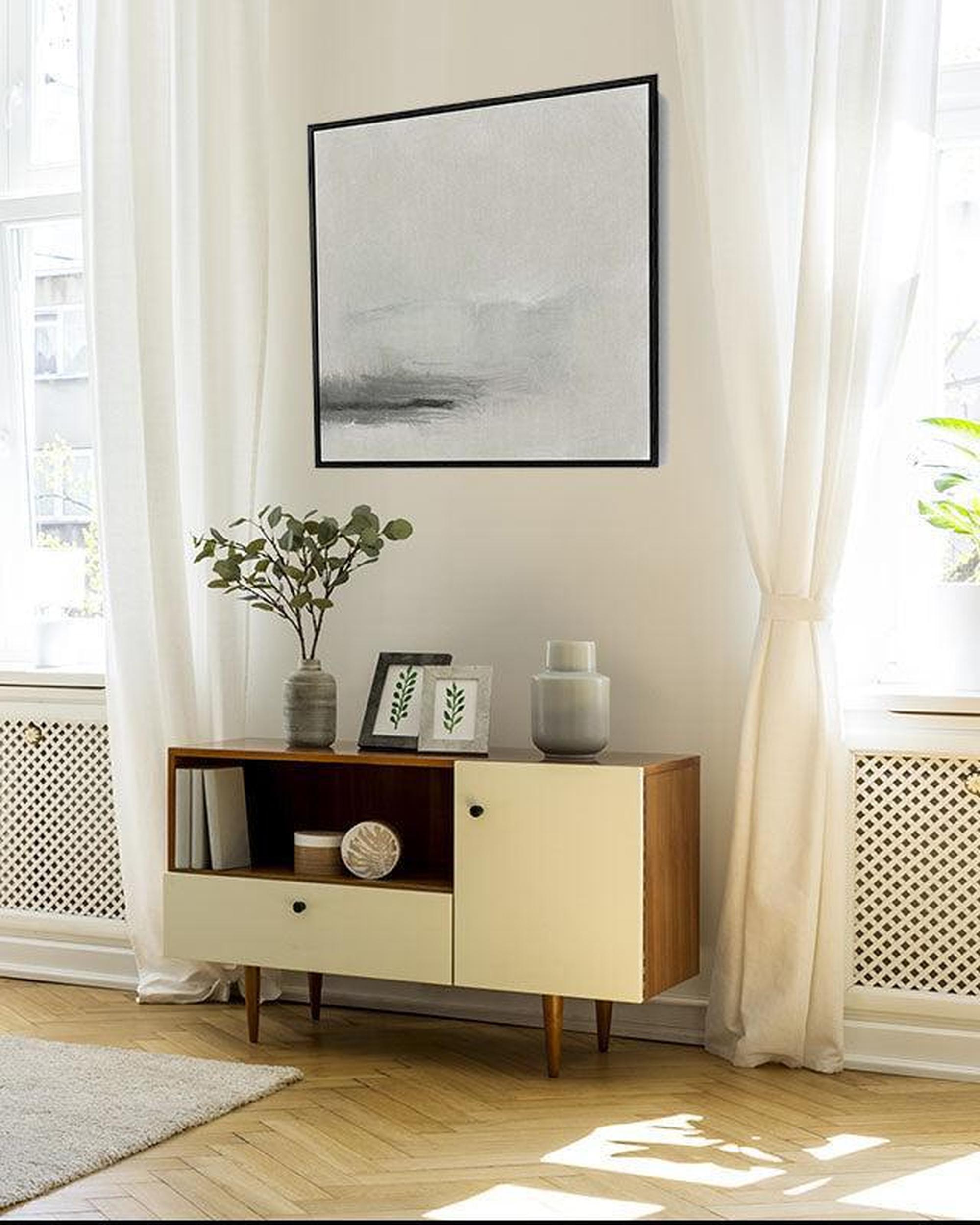 Modern wooden cabinet with decorative items in a room with white curtains and a framed picture on the wall.