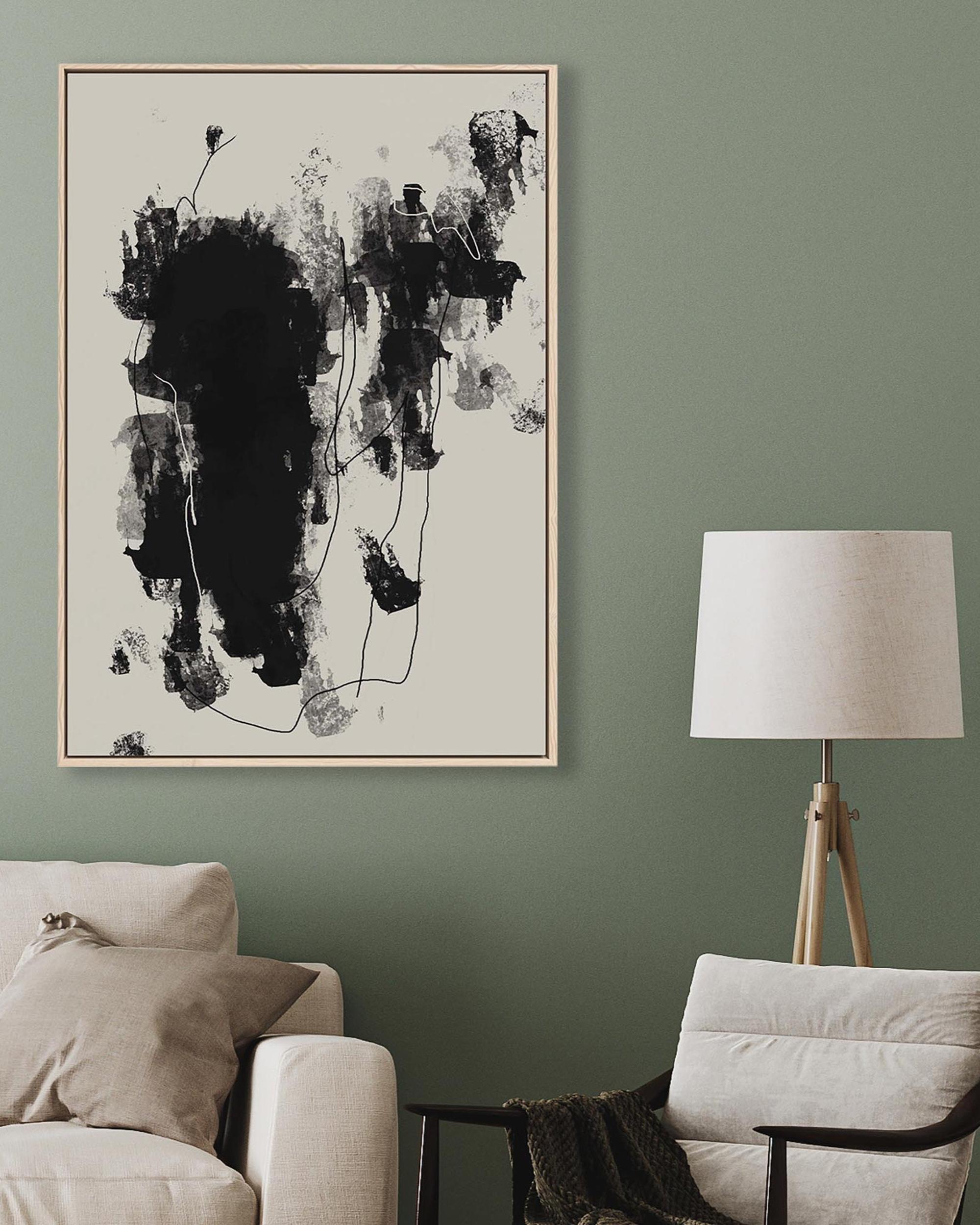 Abstract black and white painting on a green wall above a beige sofa and chair.