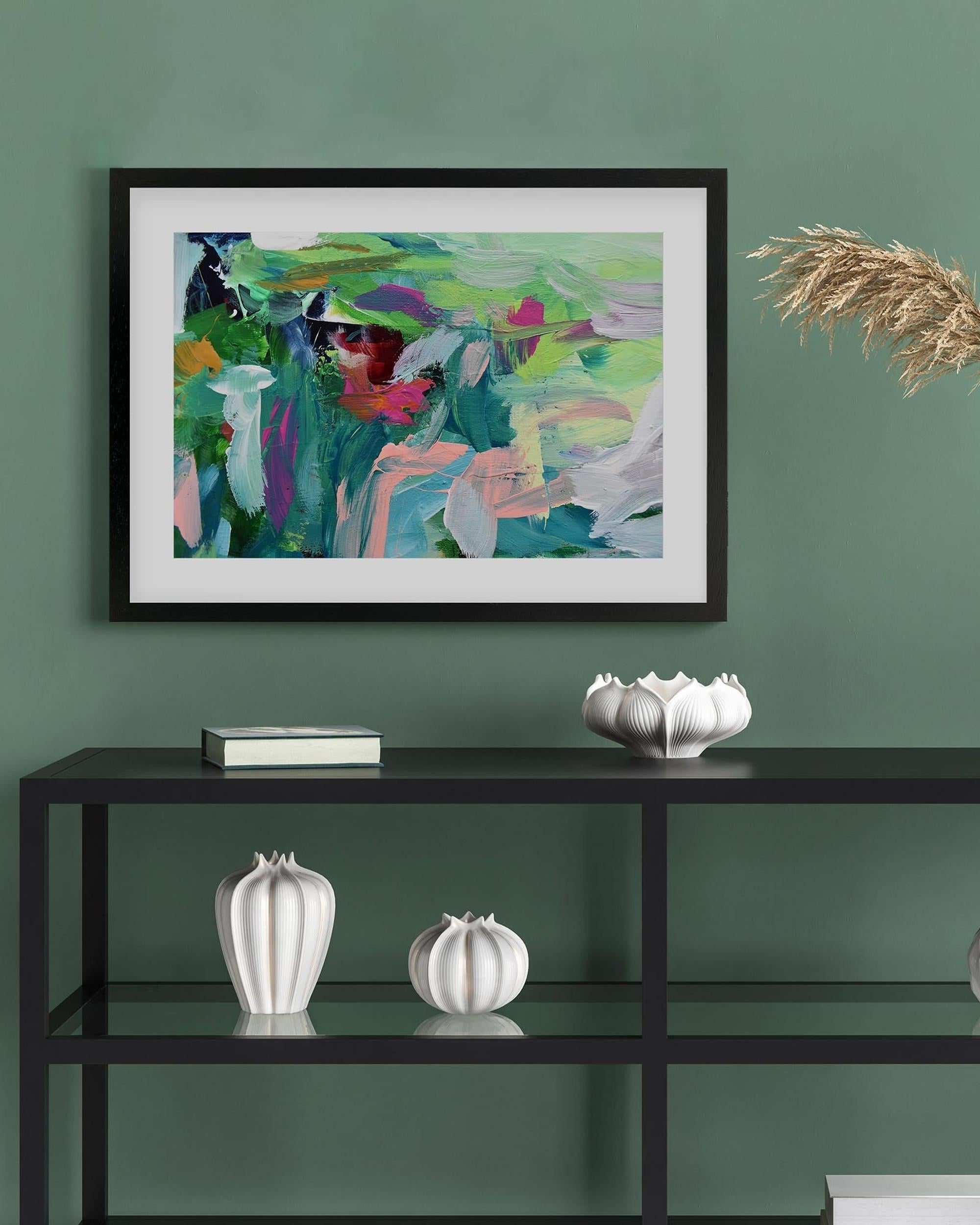 Framed abstract painting on a green wall above a black shelf with decorative items.