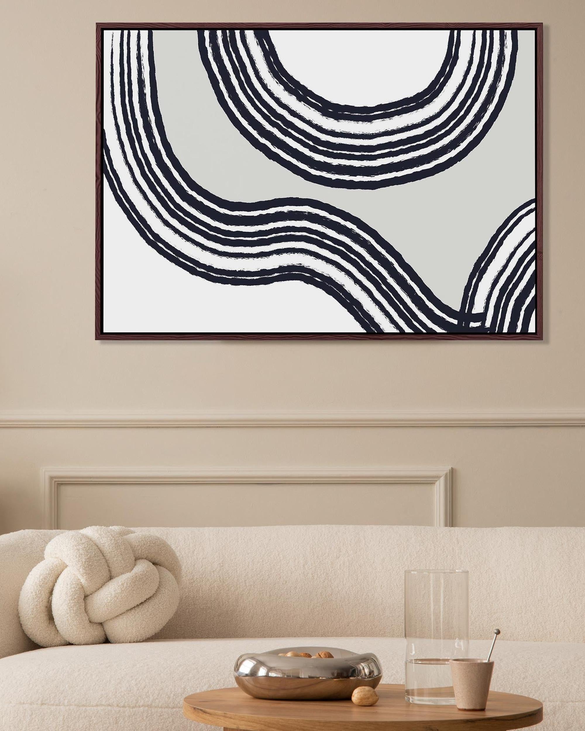 Abstract black and white wall art above a sofa in a living room.