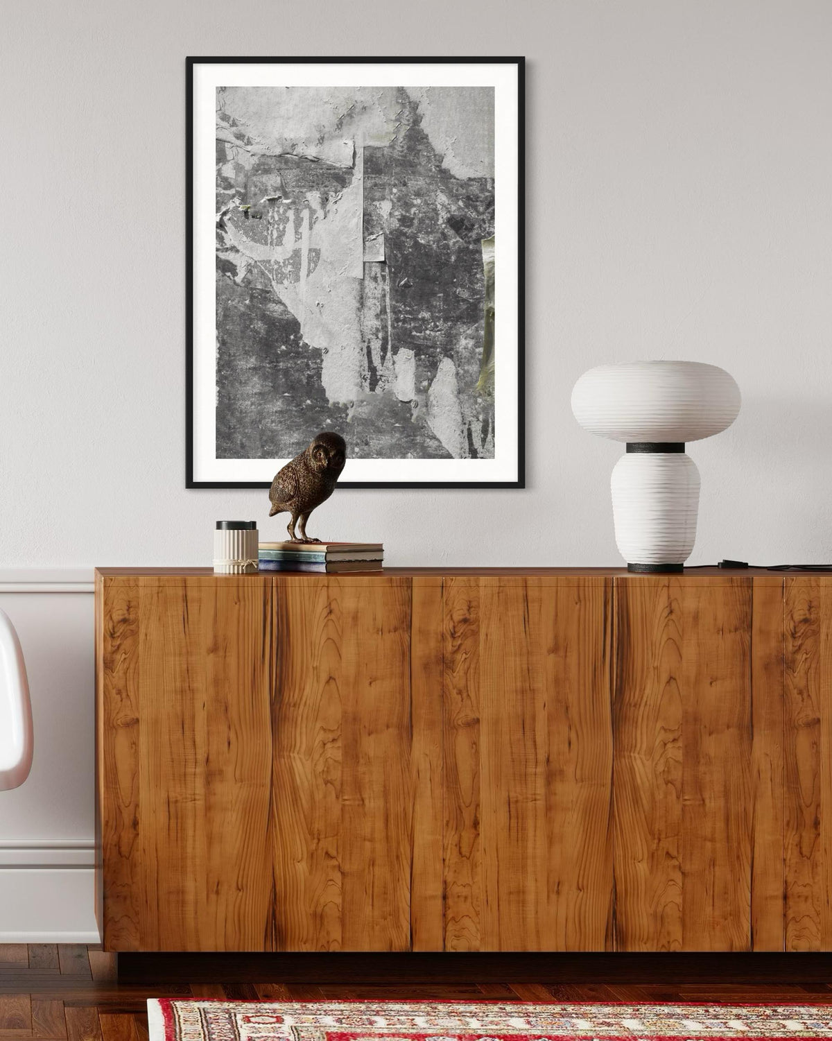 Wooden sideboard with a lamp and owl figurine, framed artwork above