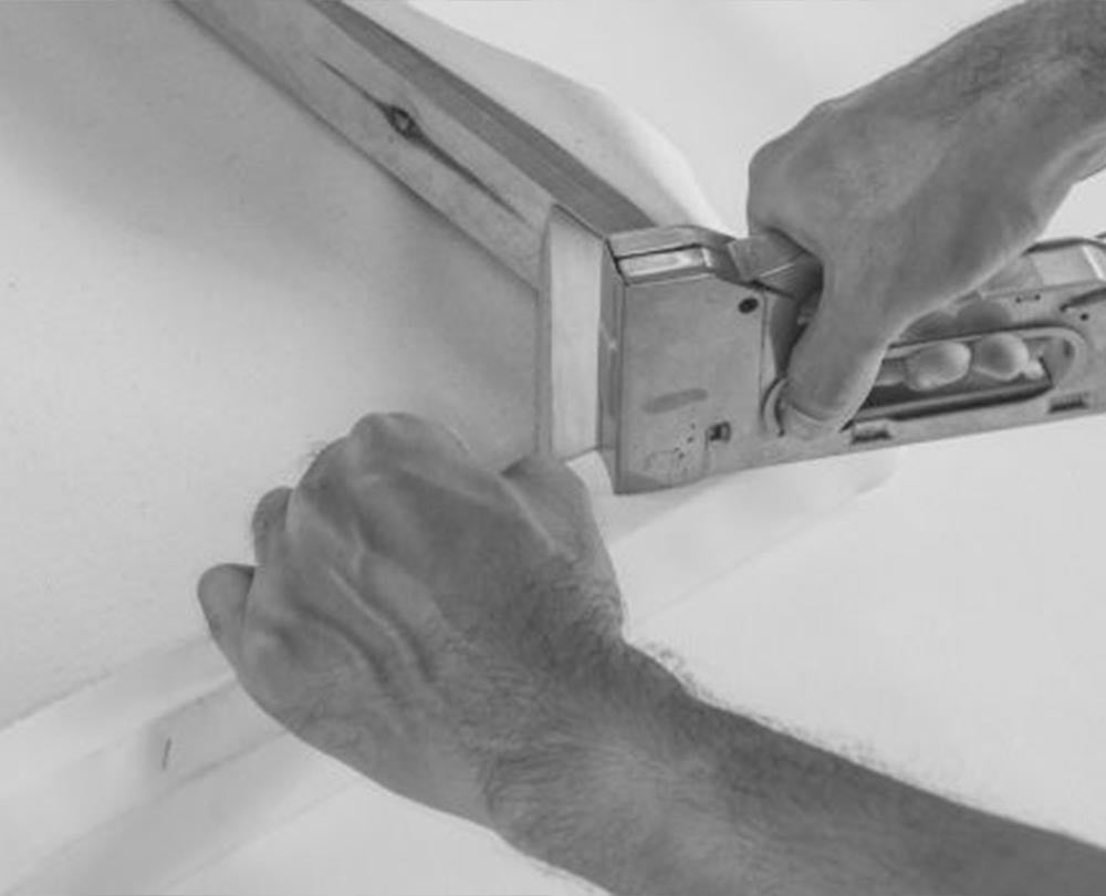 Person using a nail gun on a white surface