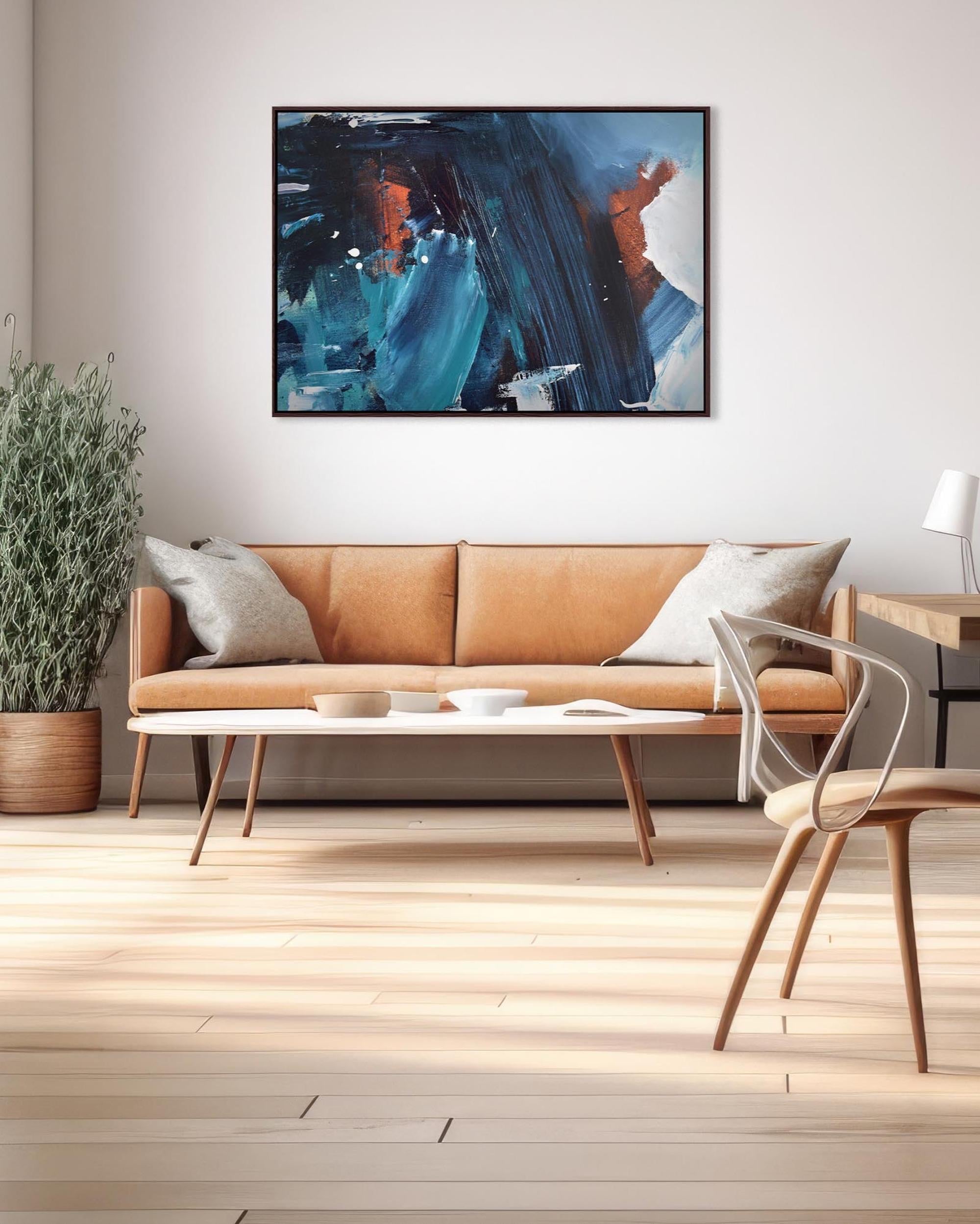 Modern living room with a tan sofa, abstract painting, and wooden floor.