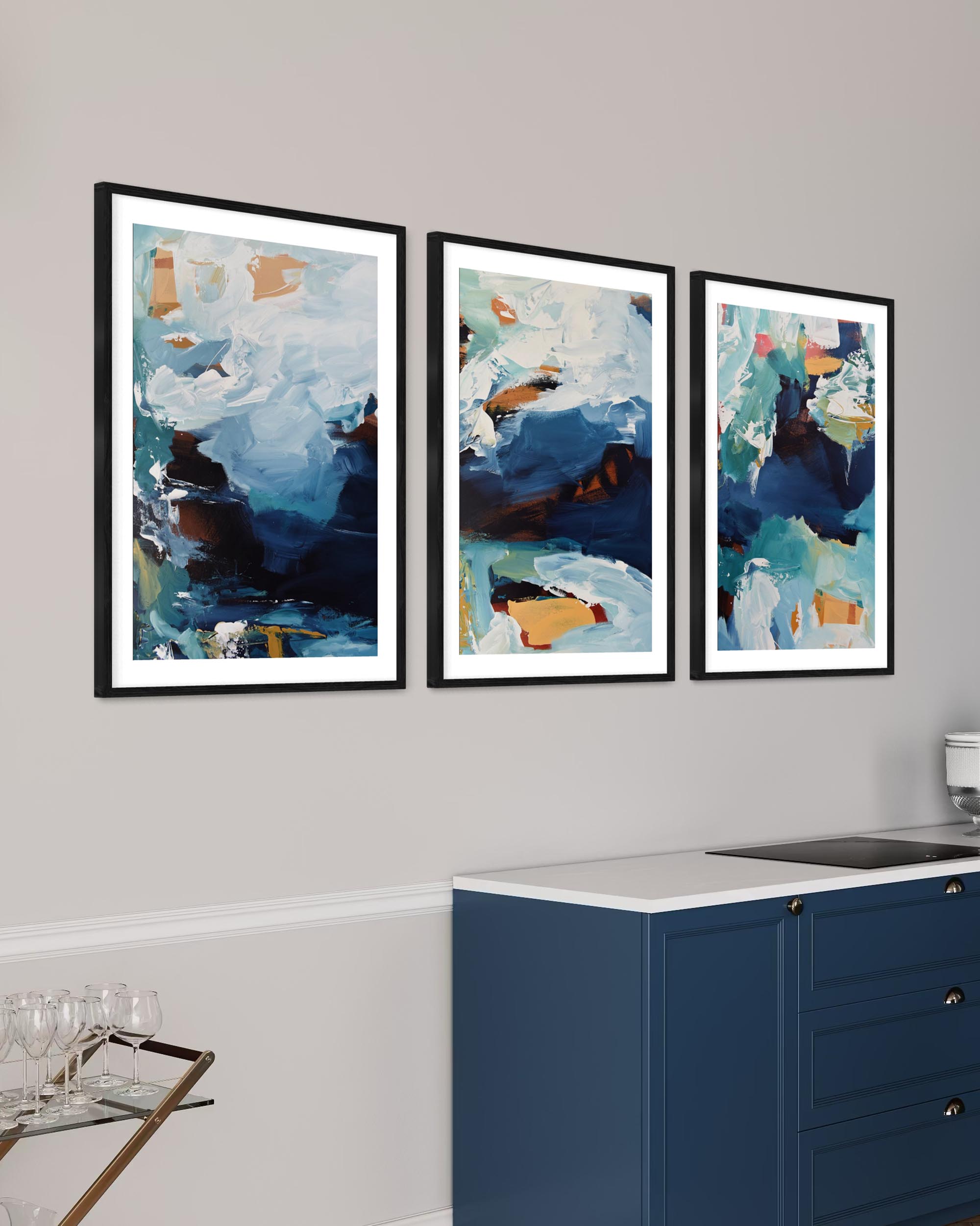 Three abstract art prints on a wall above a kitchen counter.