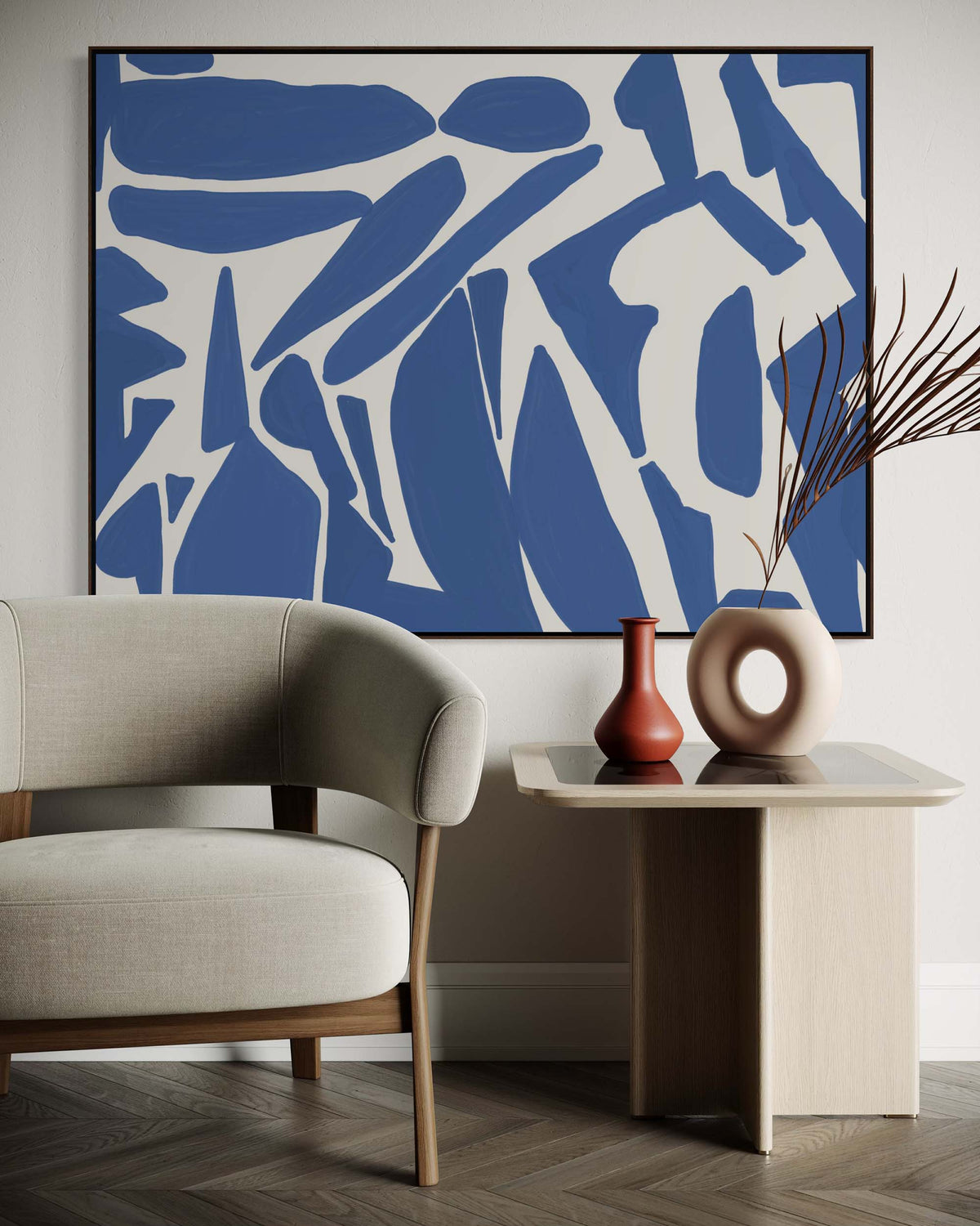Modern living room with abstract blue artwork, beige armchair, and side table with decorative vases.