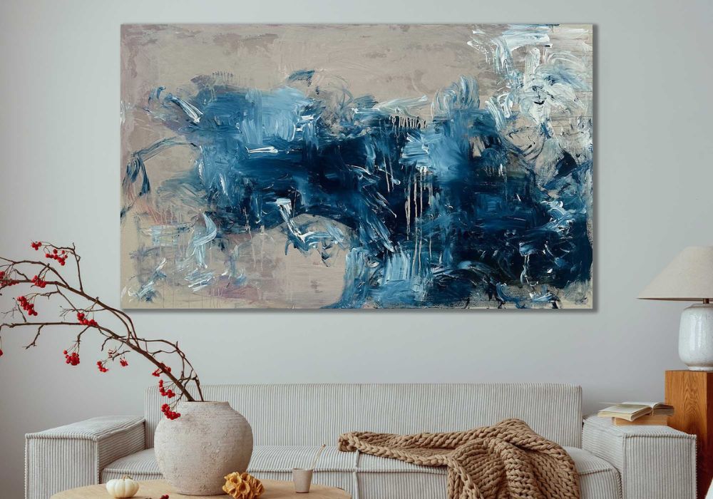 Abstract blue painting on a wall above a sofa in a living room.