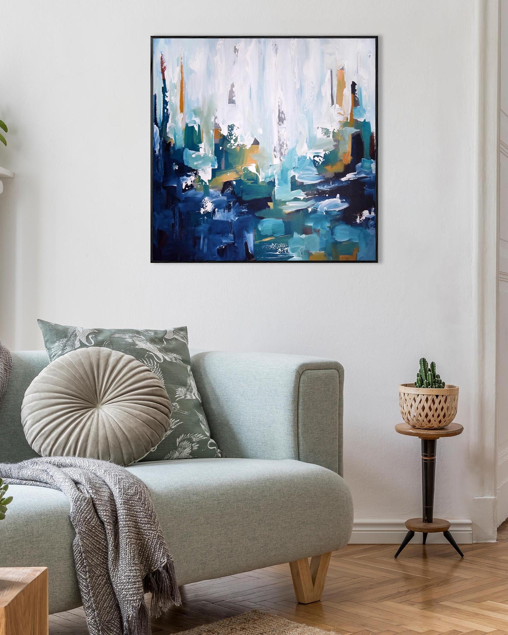 Living room with a light gray sofa, abstract painting, and small table with plant