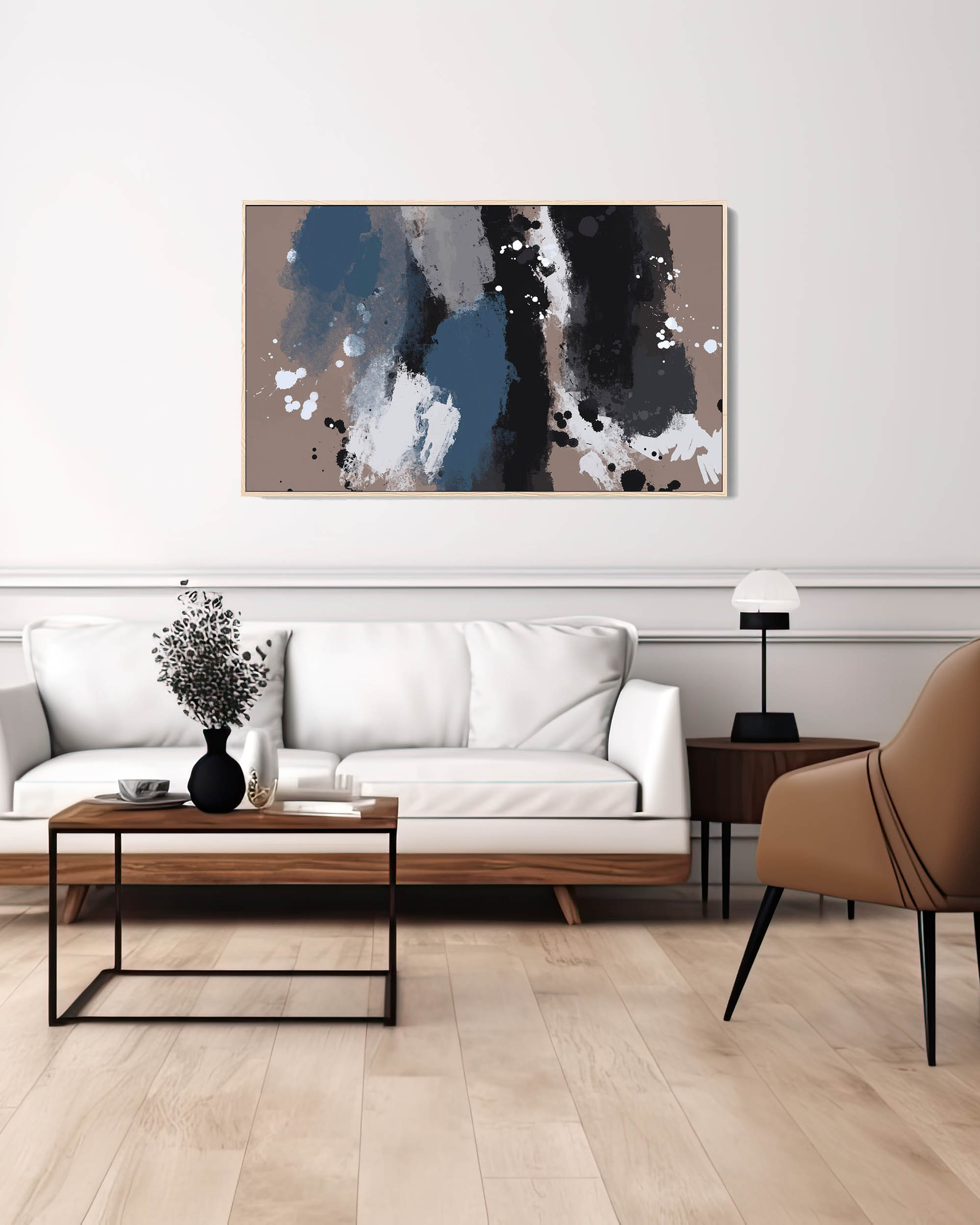 A large abstract framed canvas art hanging on a wall over a white sofa and a coffee table in a room with parquet flooring. The frame is beige, and the artwork features blocks of blue, black, and beige colors.