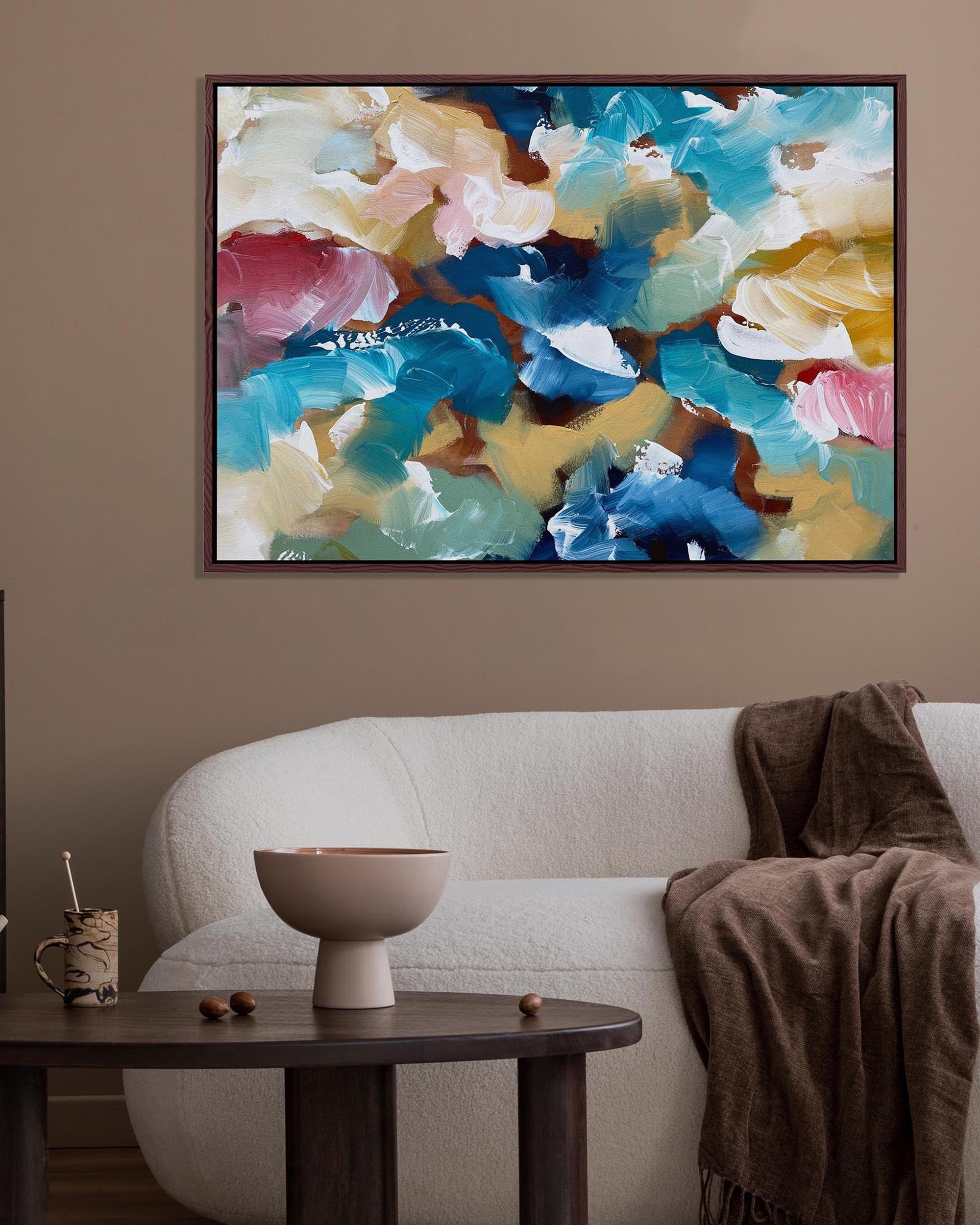 Colorful abstract painting on a wall above a sofa with decorative items on a table.