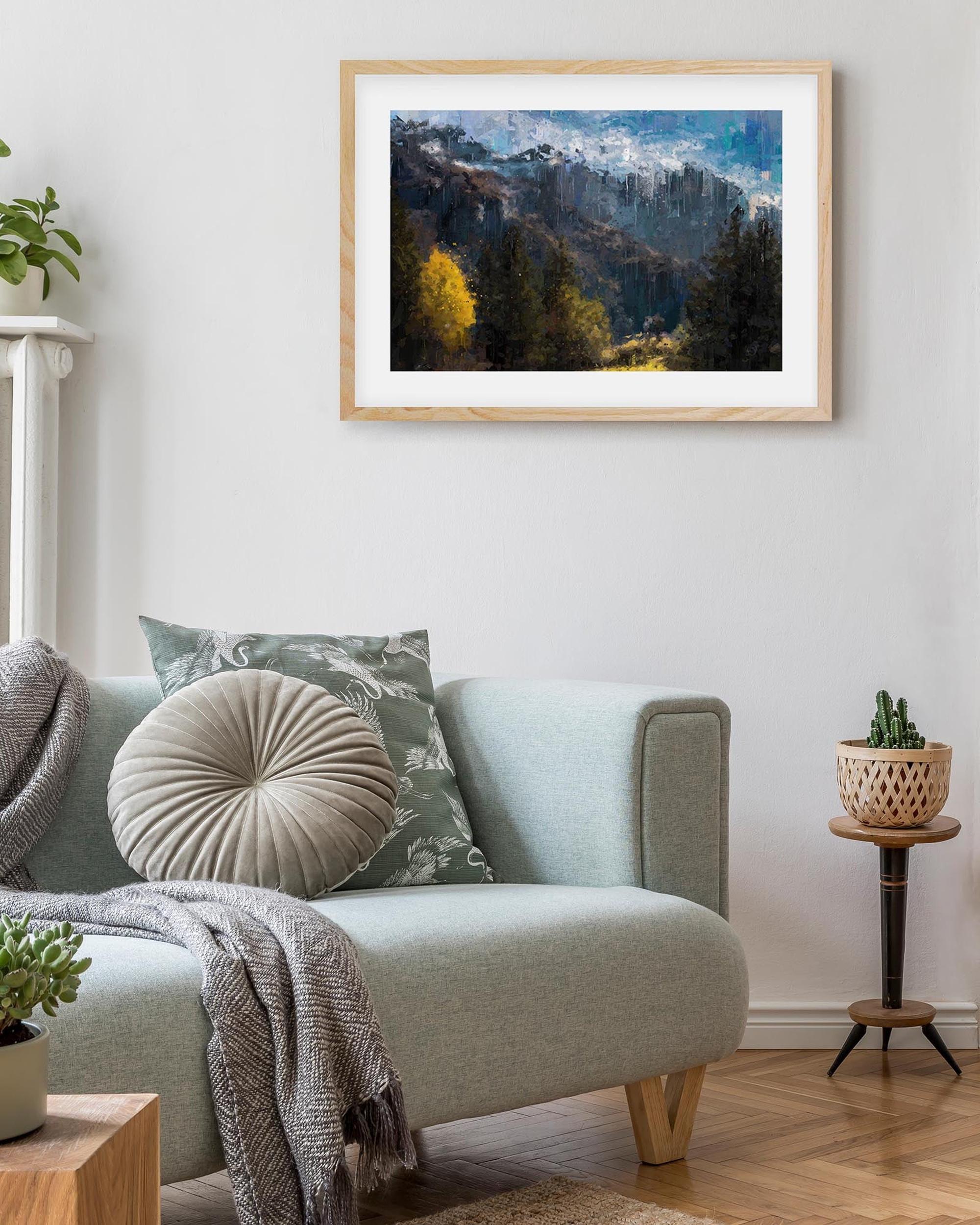 Living room with a light gray sofa, decorative pillows, and a framed mountain landscape painting on the wall.
