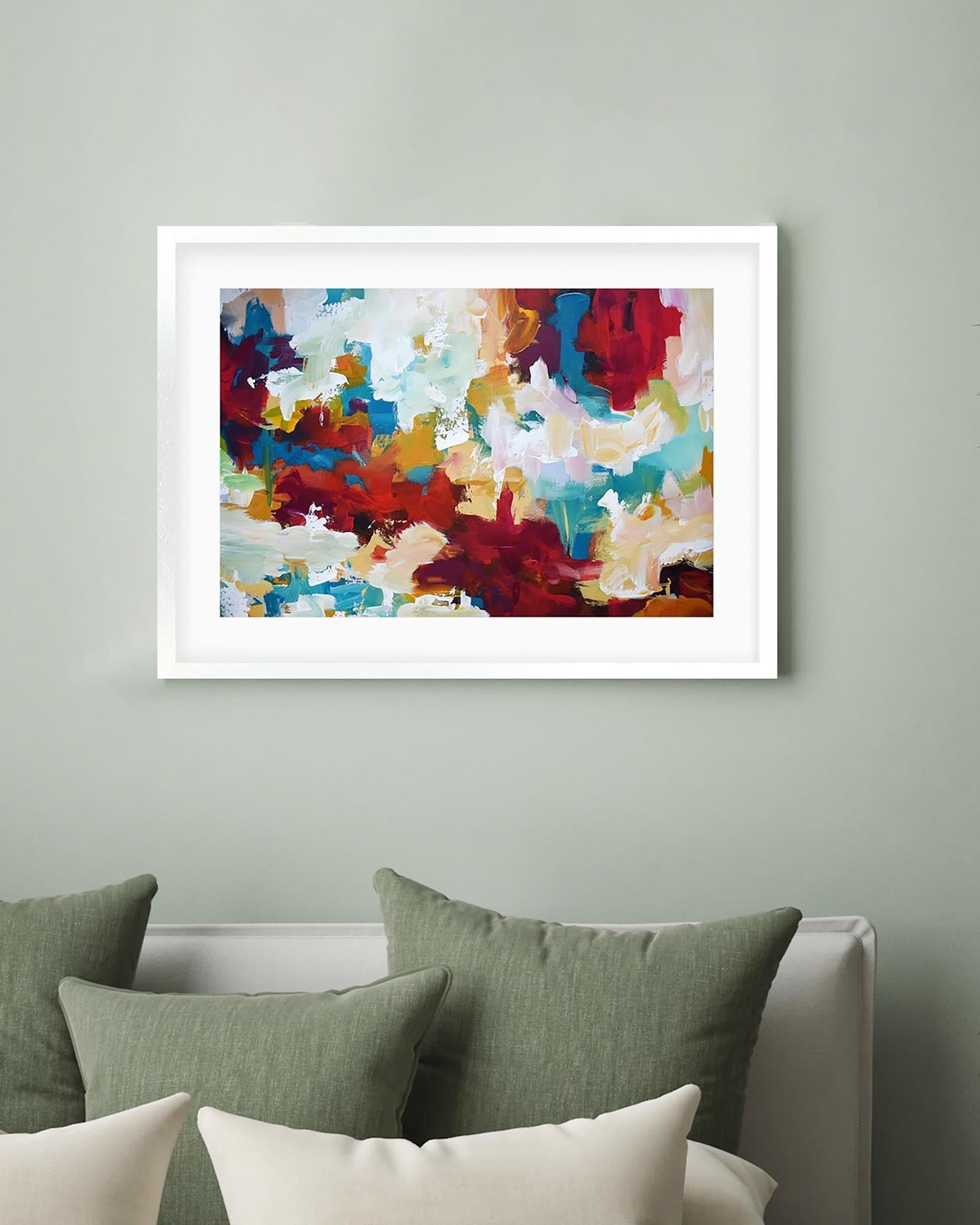 Framed abstract art on a wall above a bed with green and white pillows.