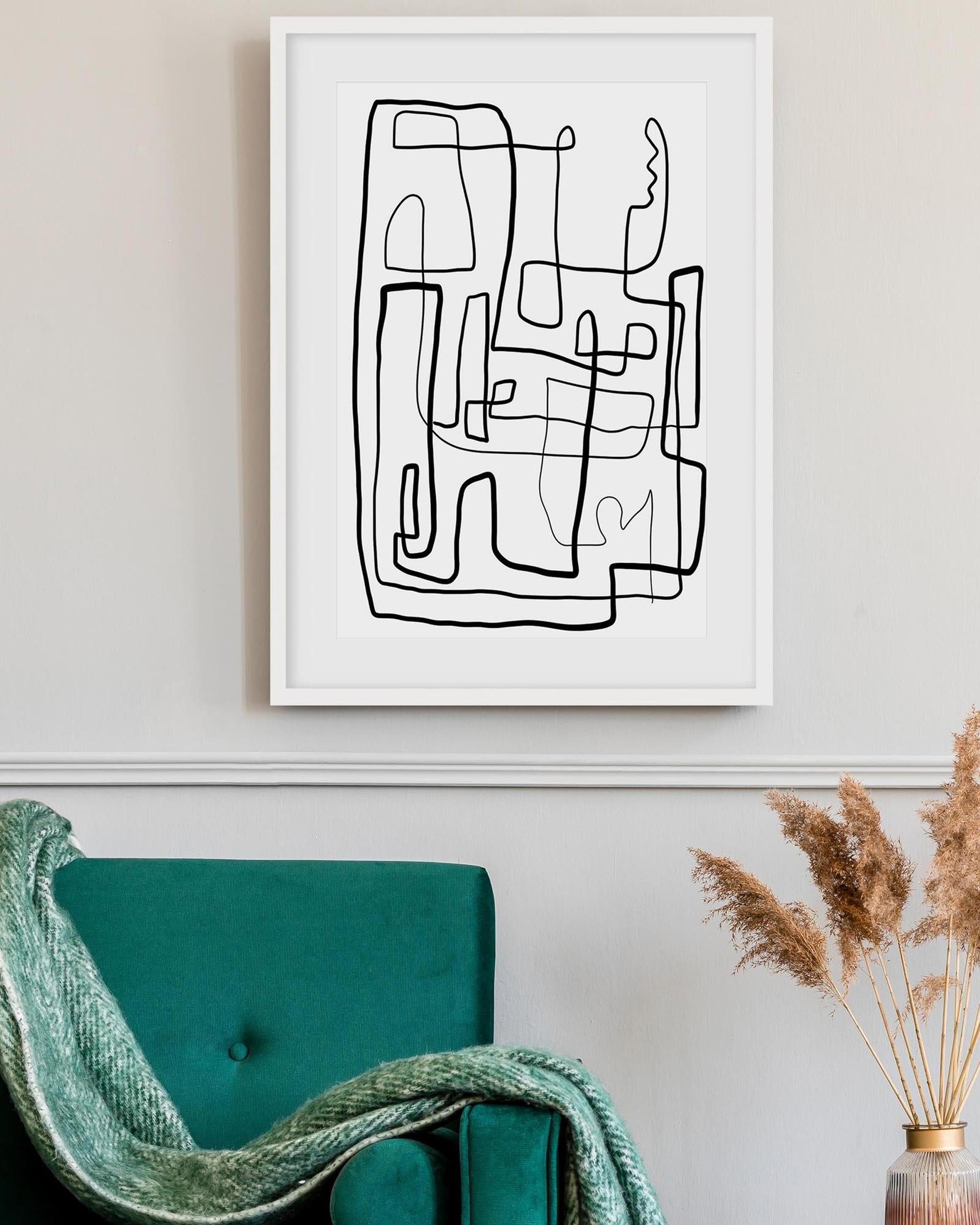 Abstract line art print on a wall above a teal chair with a green blanket.