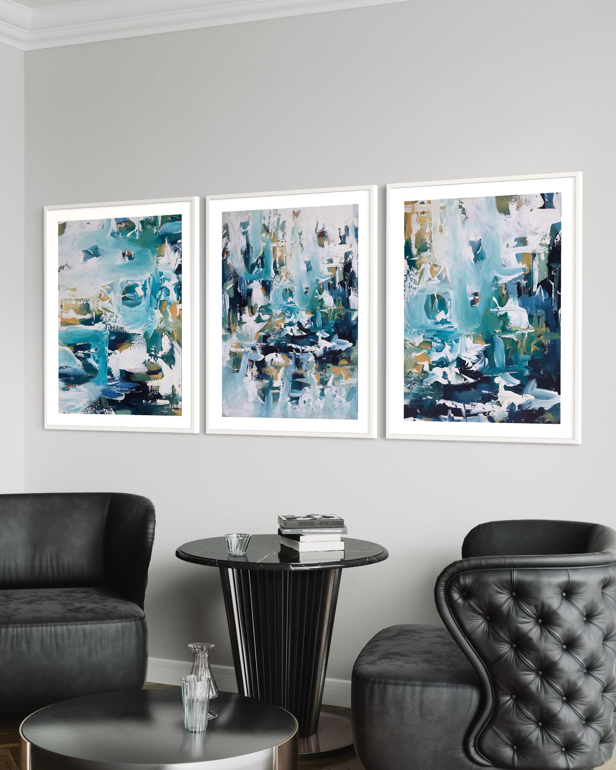 Three abstract art pieces in white frames on a gray wall above a black chair and table.