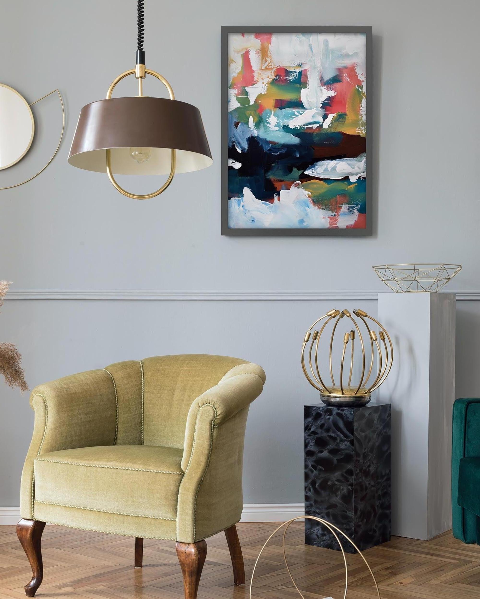 Living room with a green armchair, abstract painting, and decorative lamp.