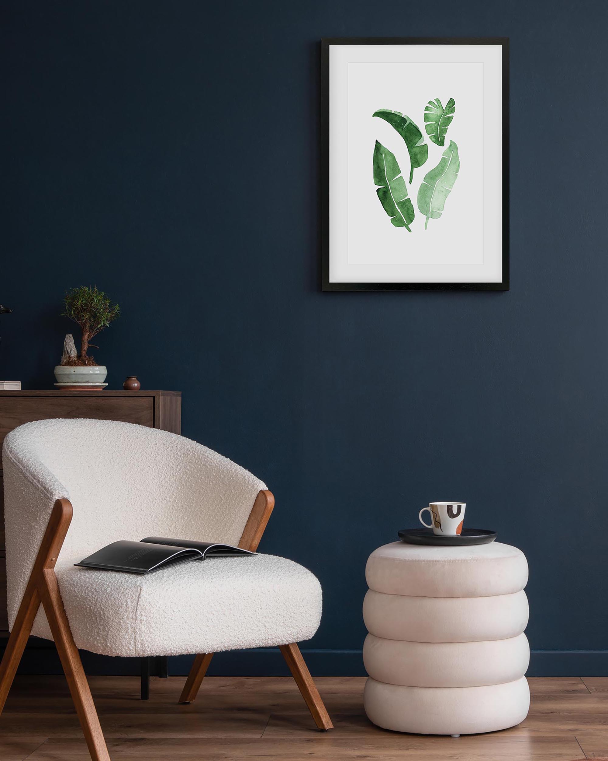framed botanical art print on a blue wall by an armchair