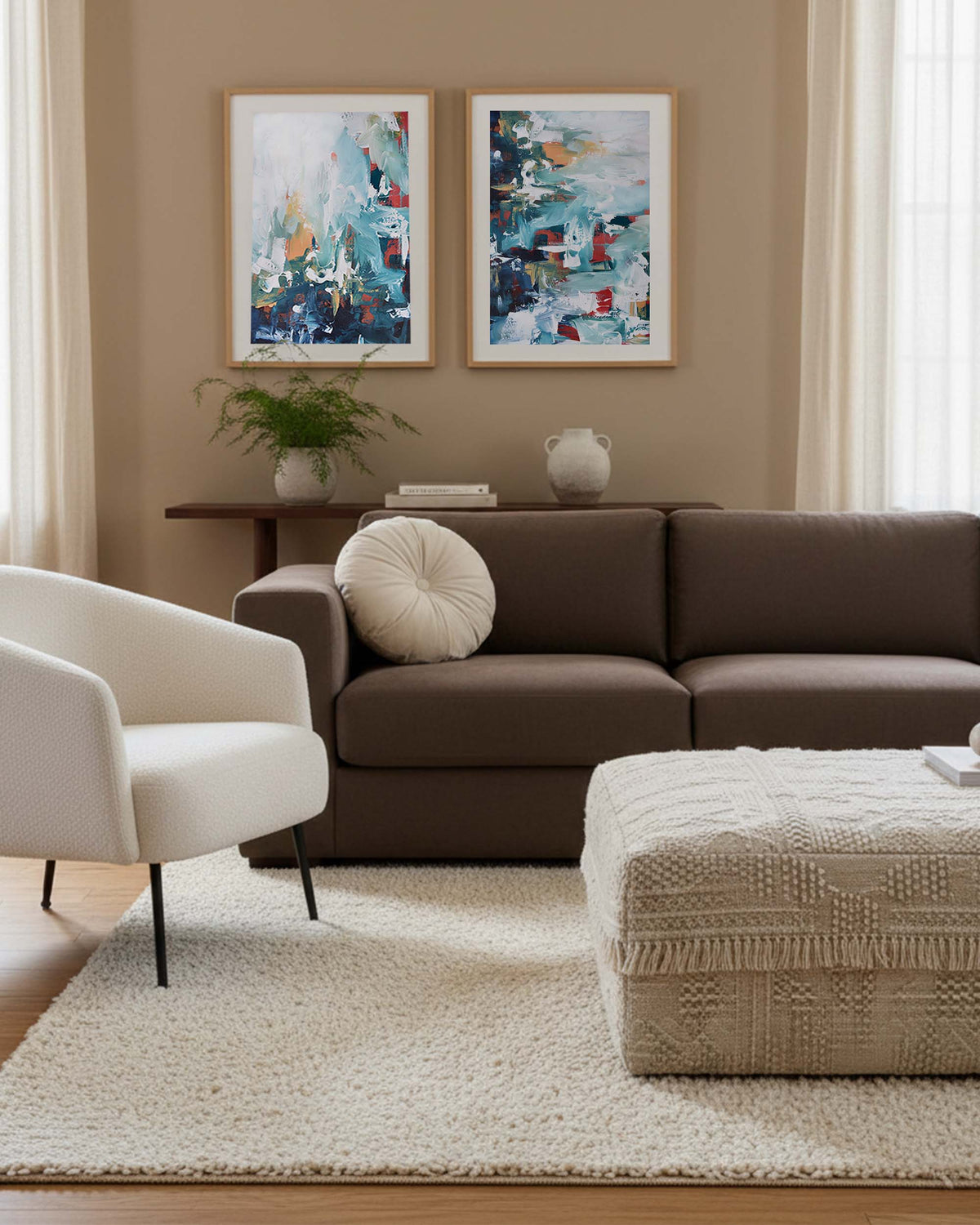 Living room with brown sofa, white armchair, and abstract art on beige walls.