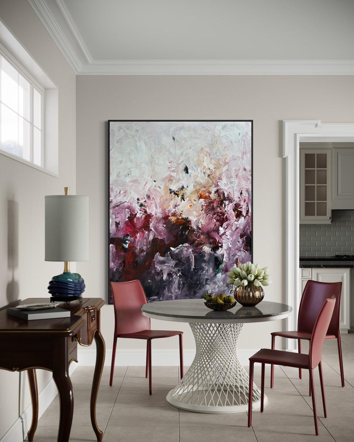 Dining room with a large abstract painting on the wall, round table, and chairs.