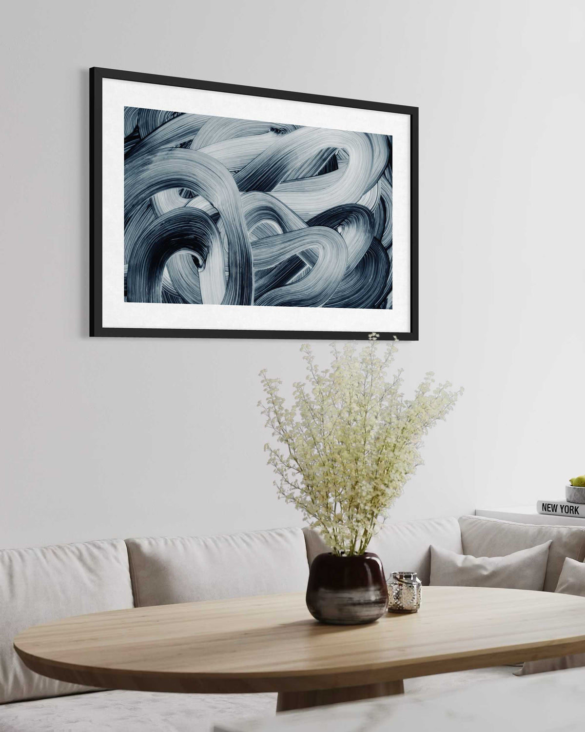 Framed abstract art piece on a wall above a coffee table with decorative items.