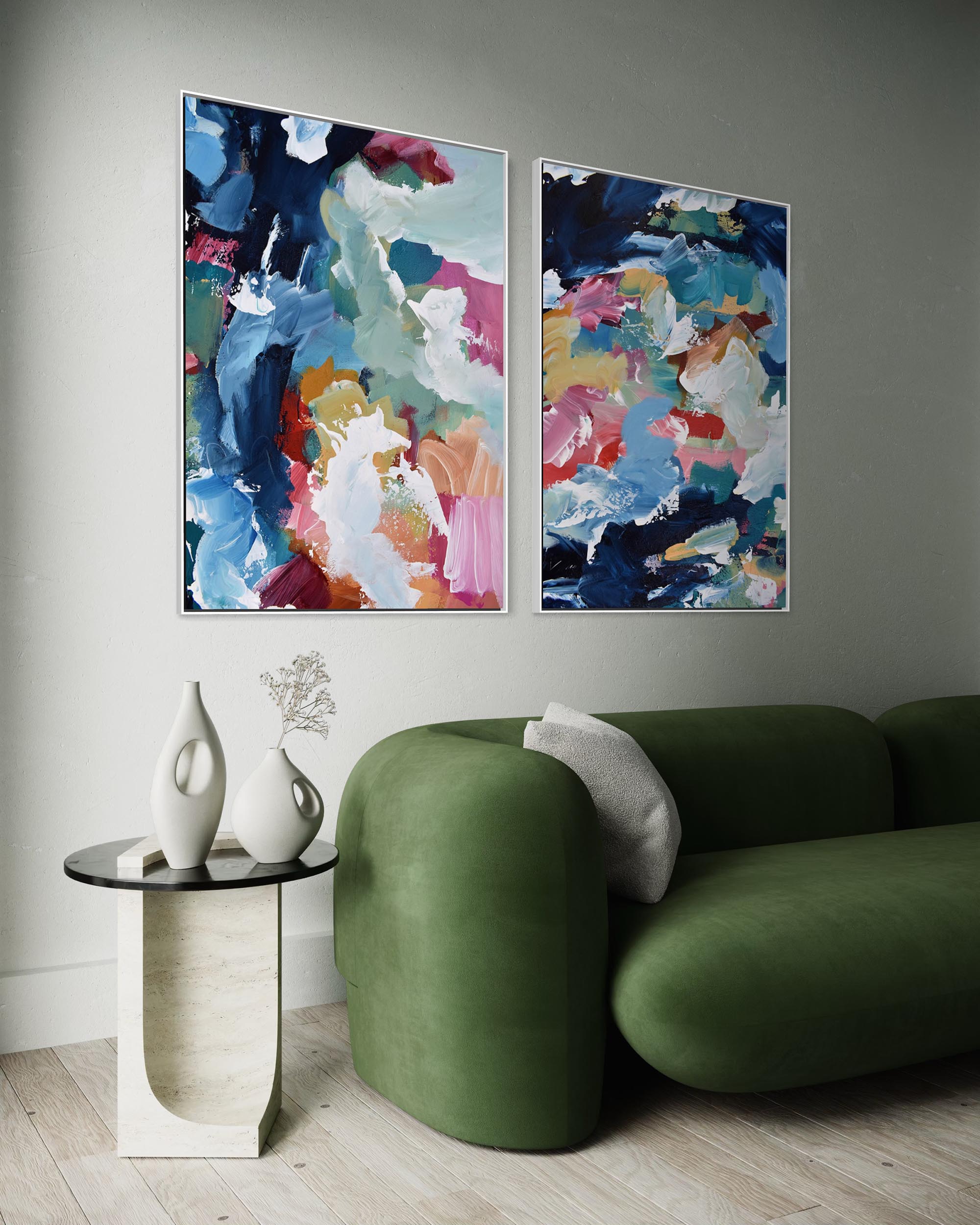 Two abstract paintings on a gray wall above a green sofa.