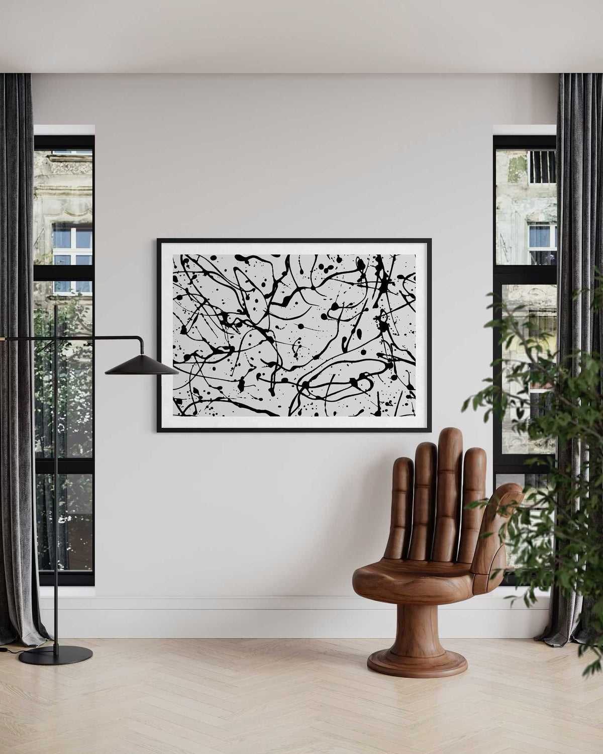 Abstract black and white artwork on a wall in a modern living room with a wooden chair and plant.