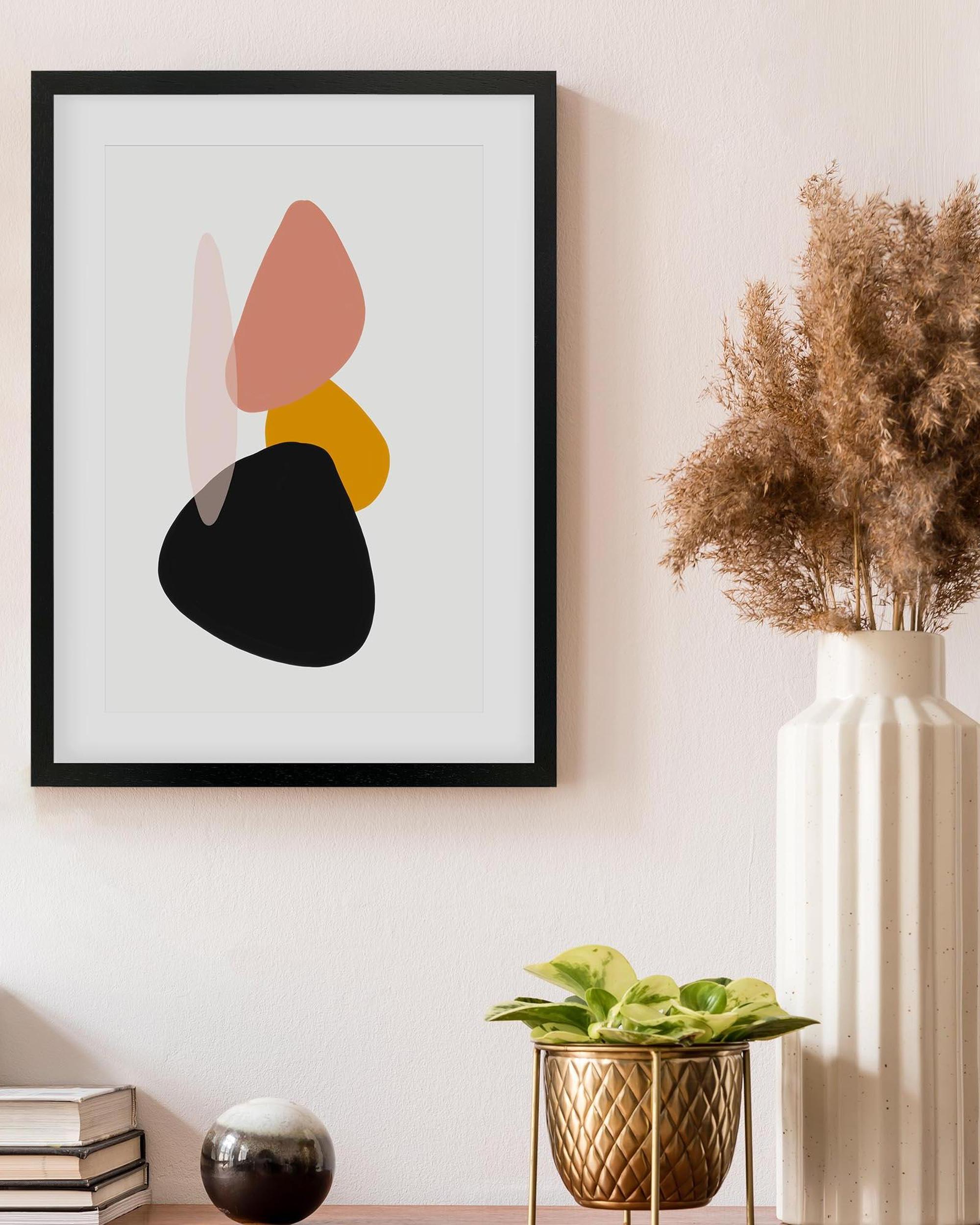Framed abstract art piece on a wall with decorative elements below.