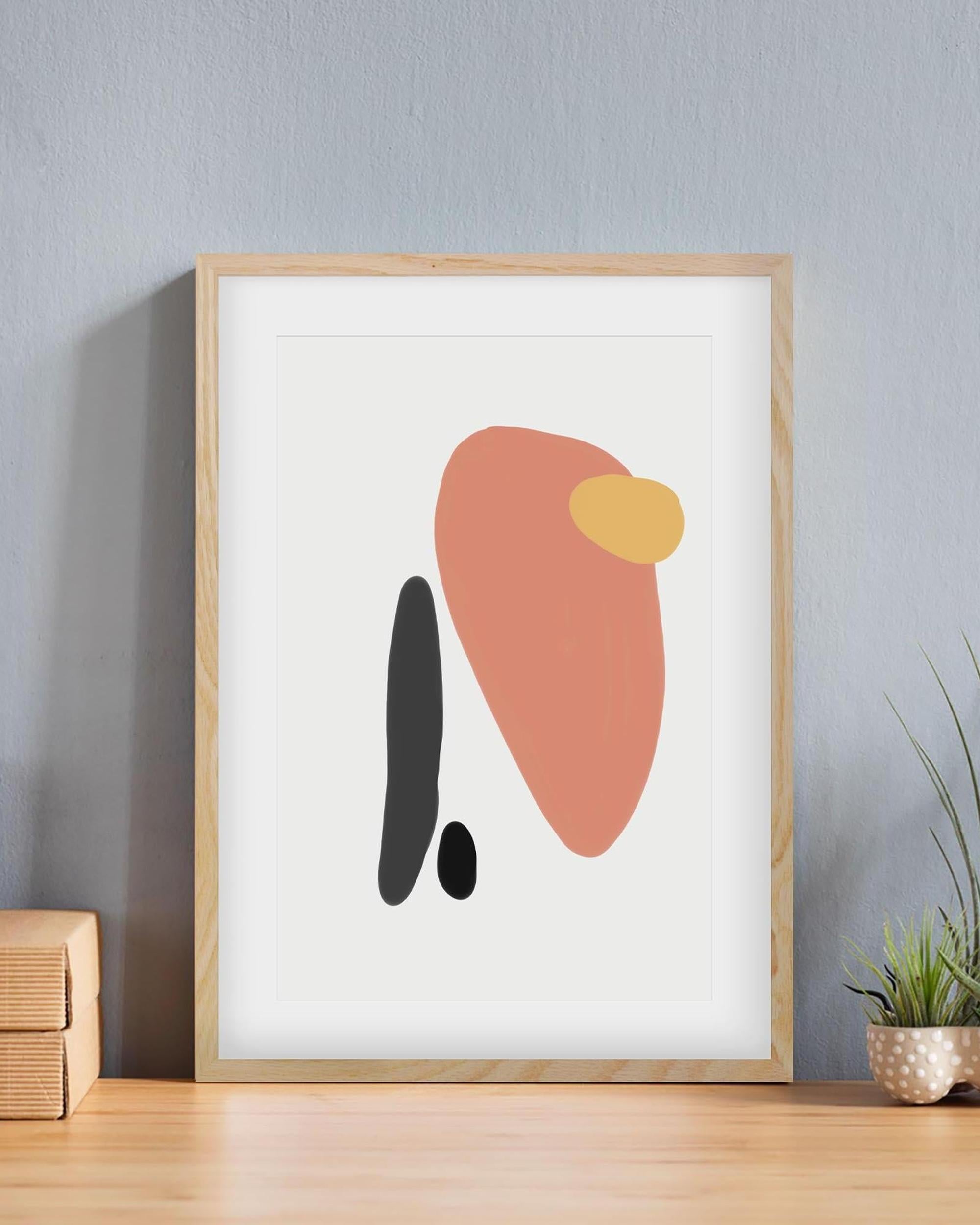 Framed abstract art print with geometric shapes on a white background, displayed on a wooden surface.