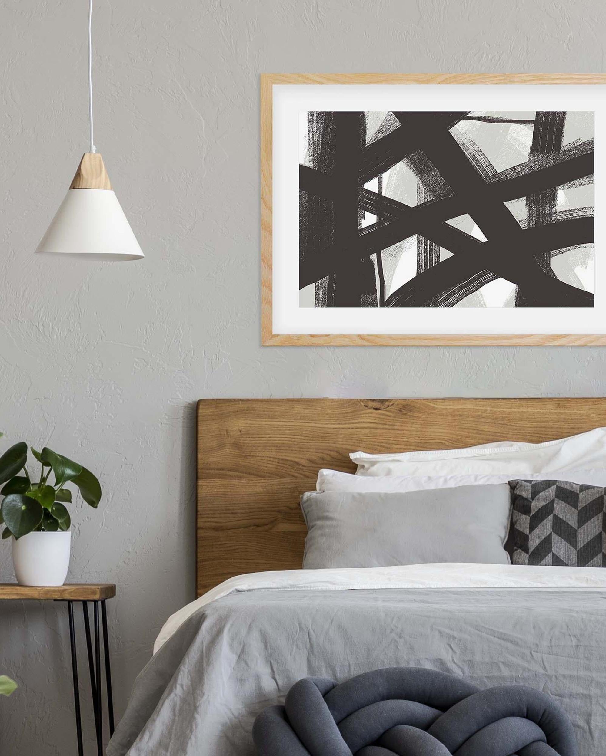 Modern bedroom with wooden headboard, abstract art, and minimal decor.
