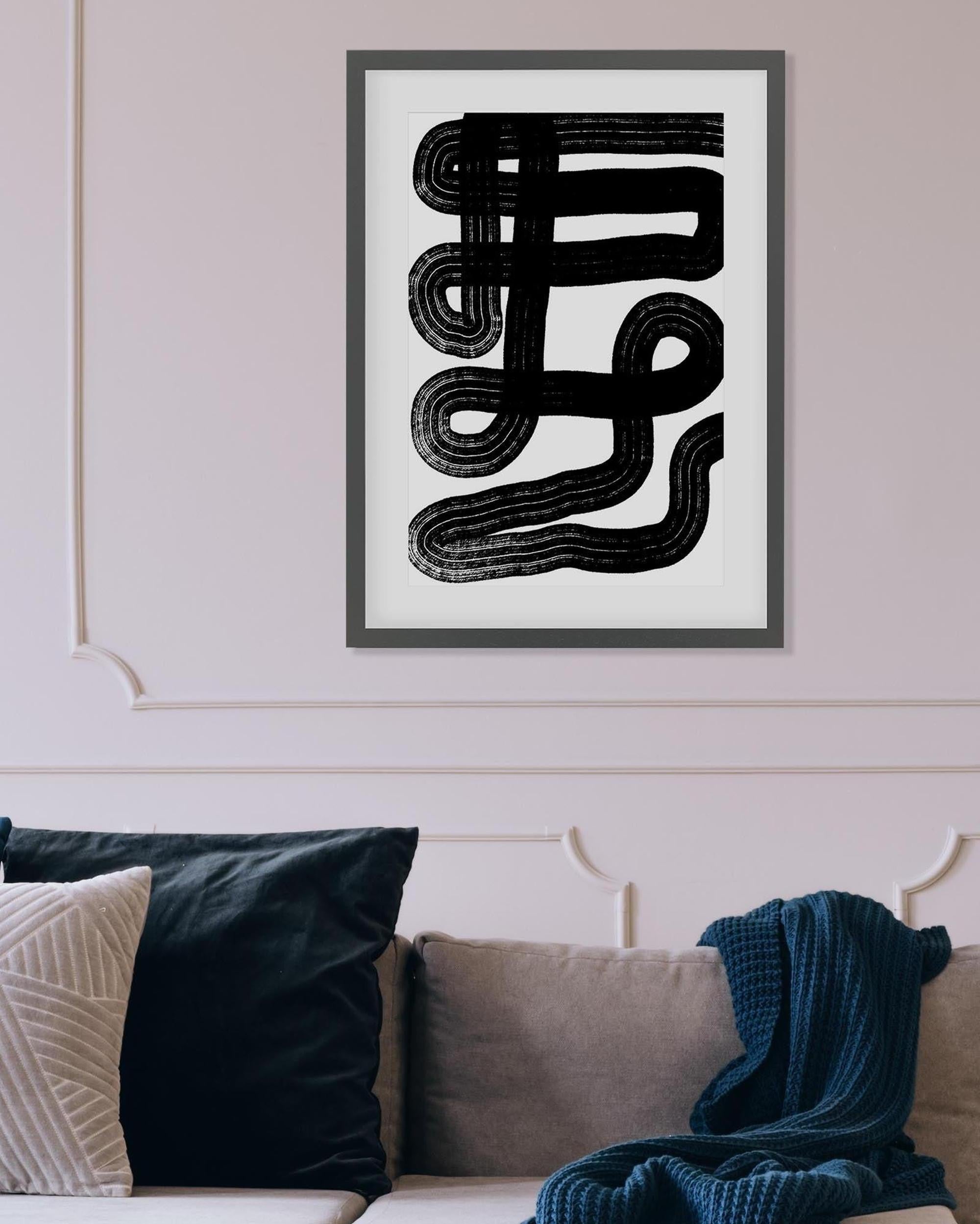 Framed abstract art piece on a wall above a sofa with cushions and a blanket.
