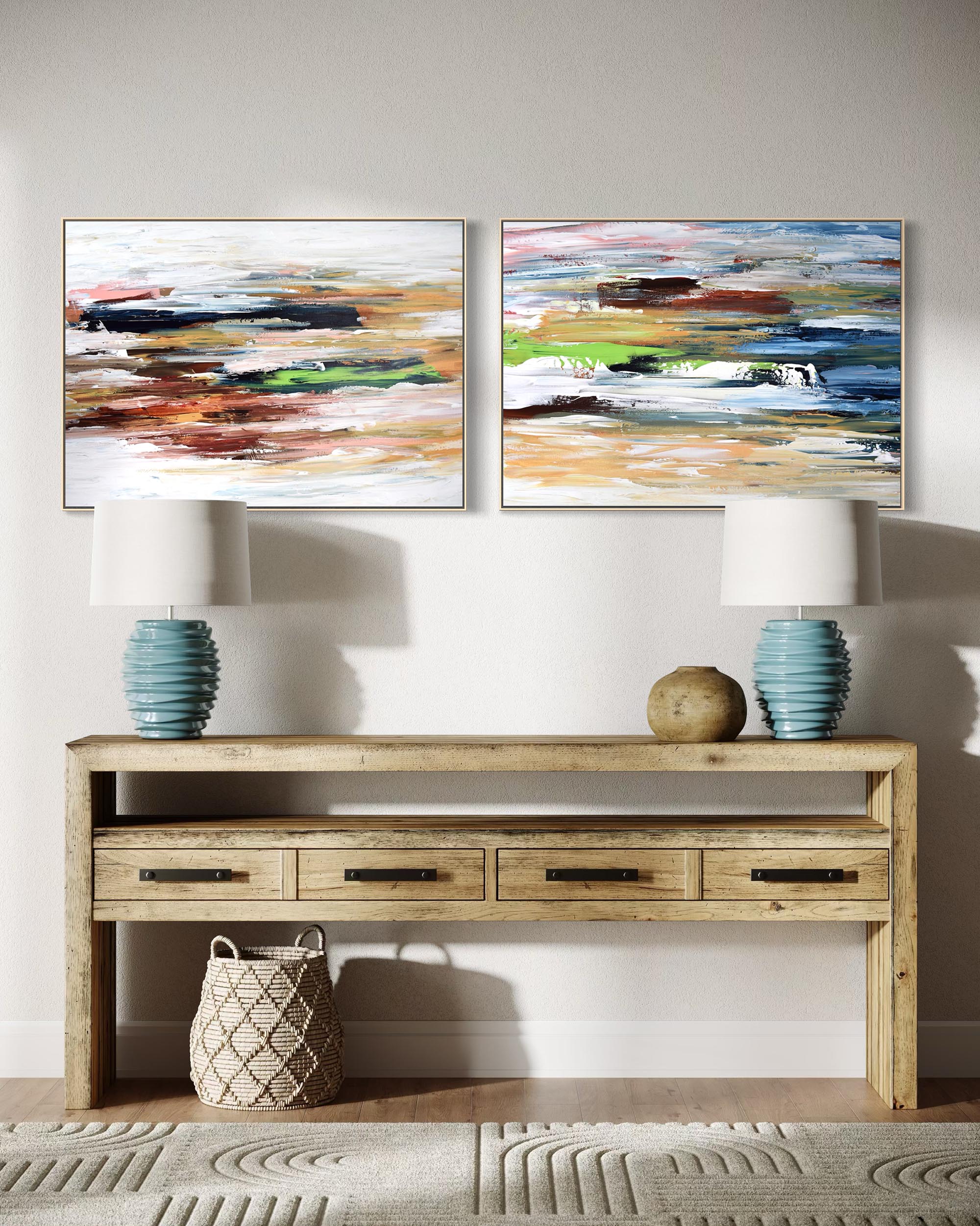Two abstract paintings above a wooden console table with lamps and decor items.