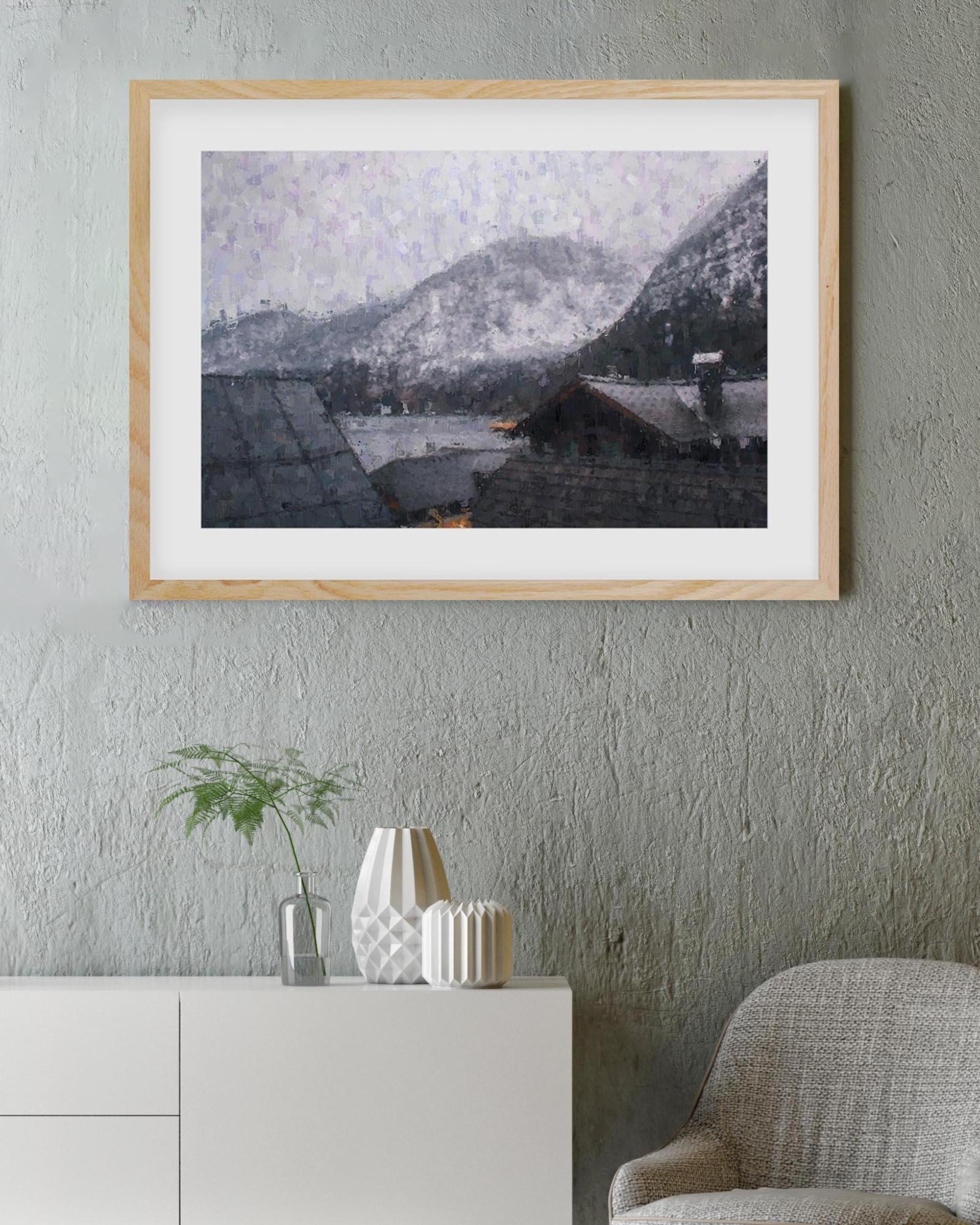 Framed artwork of a snowy mountain scene on a gray wall with a white cabinet and plant below.