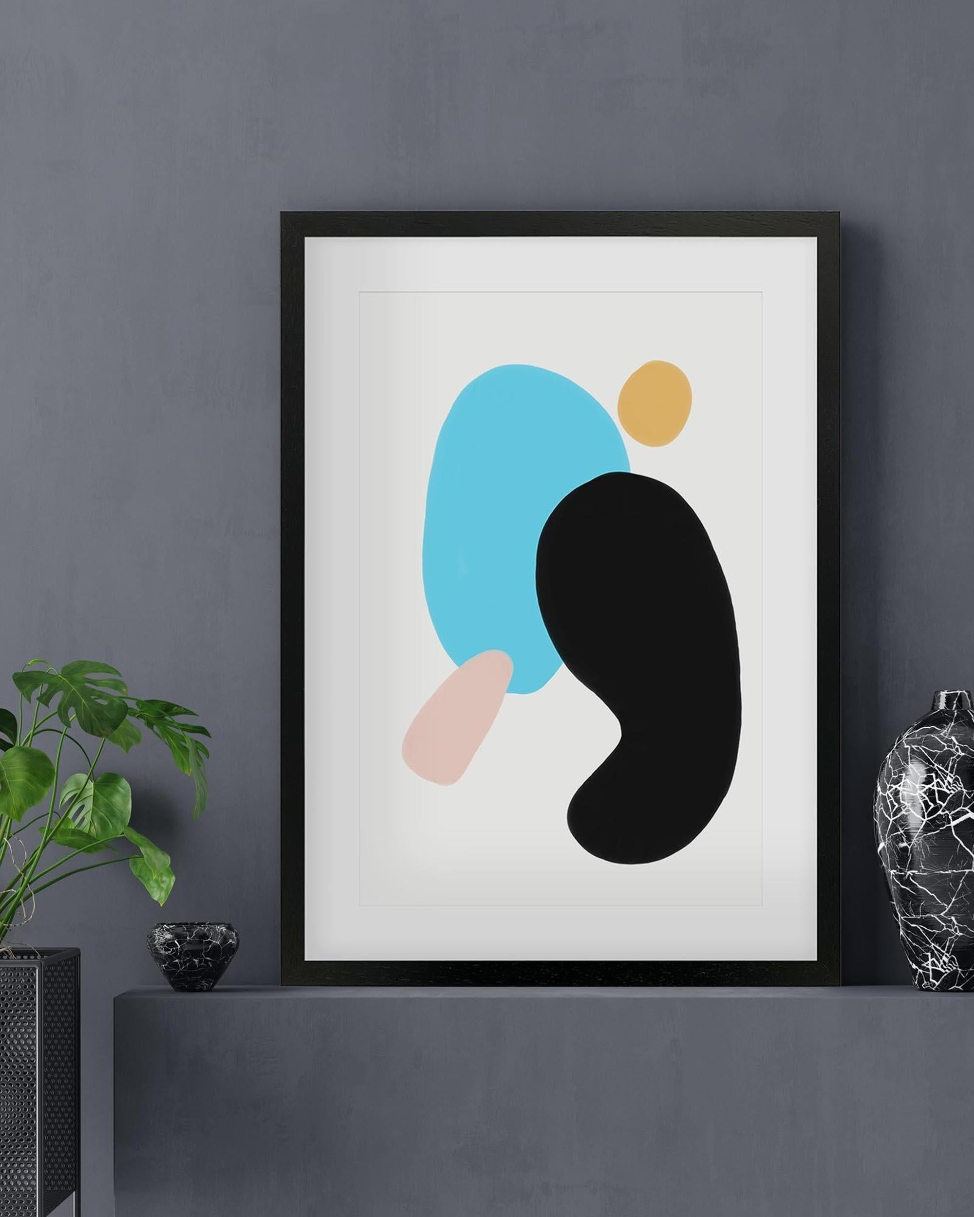 Framed abstract art print with colorful shapes on a gray wall.