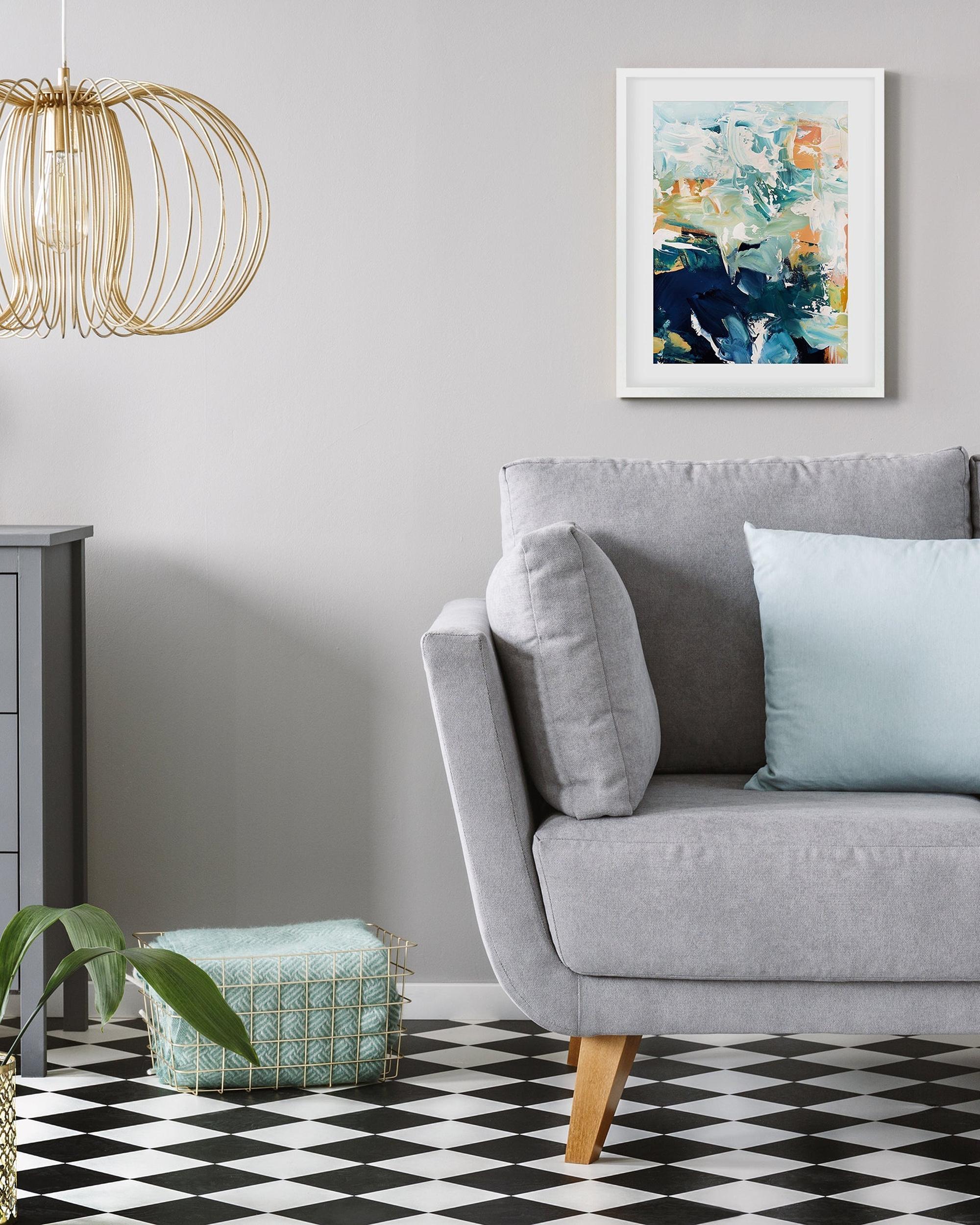Modern living room with a gray sofa, abstract art, and geometric floor pattern.