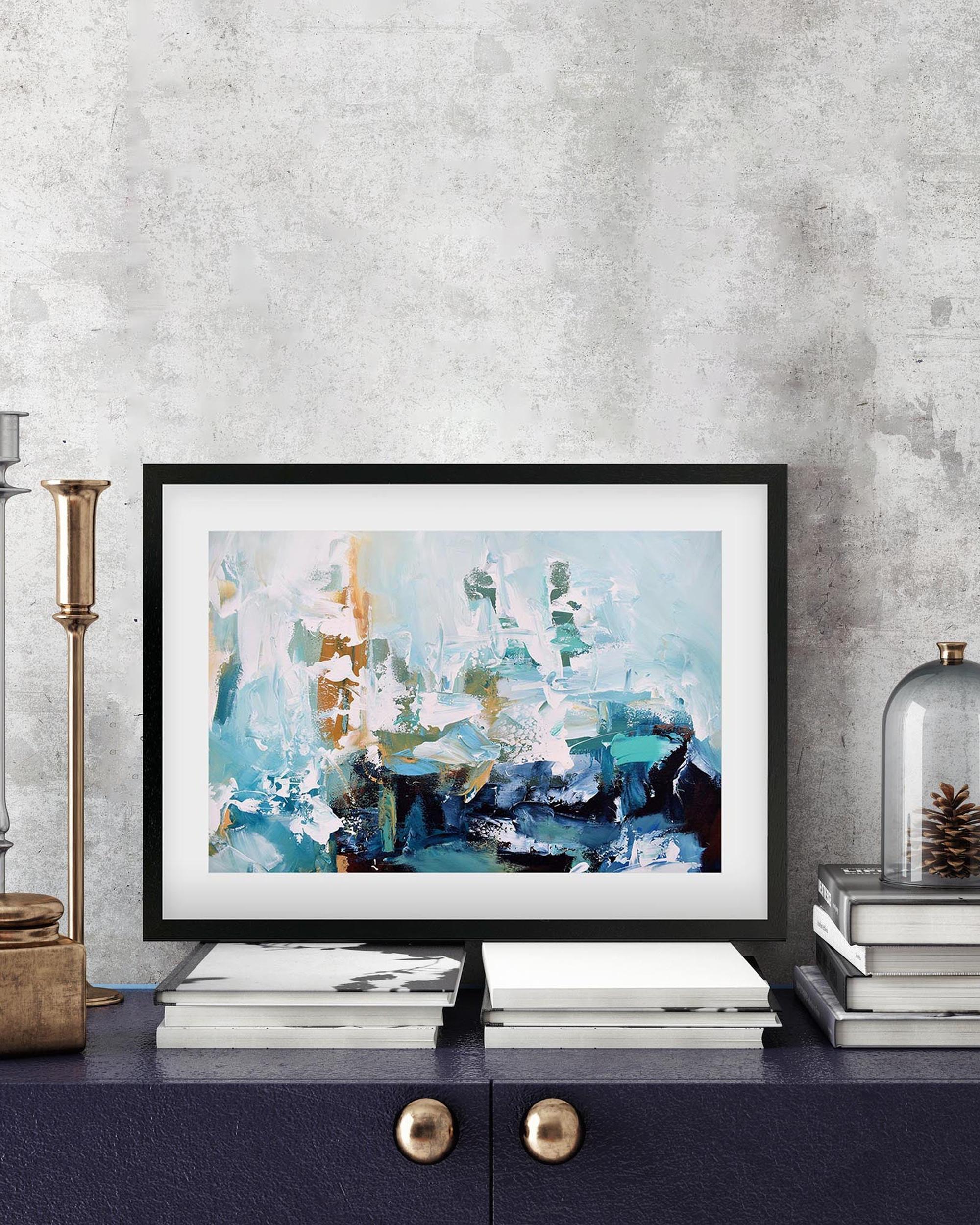 Framed abstract art piece on a shelf with decorative items against a textured wall.