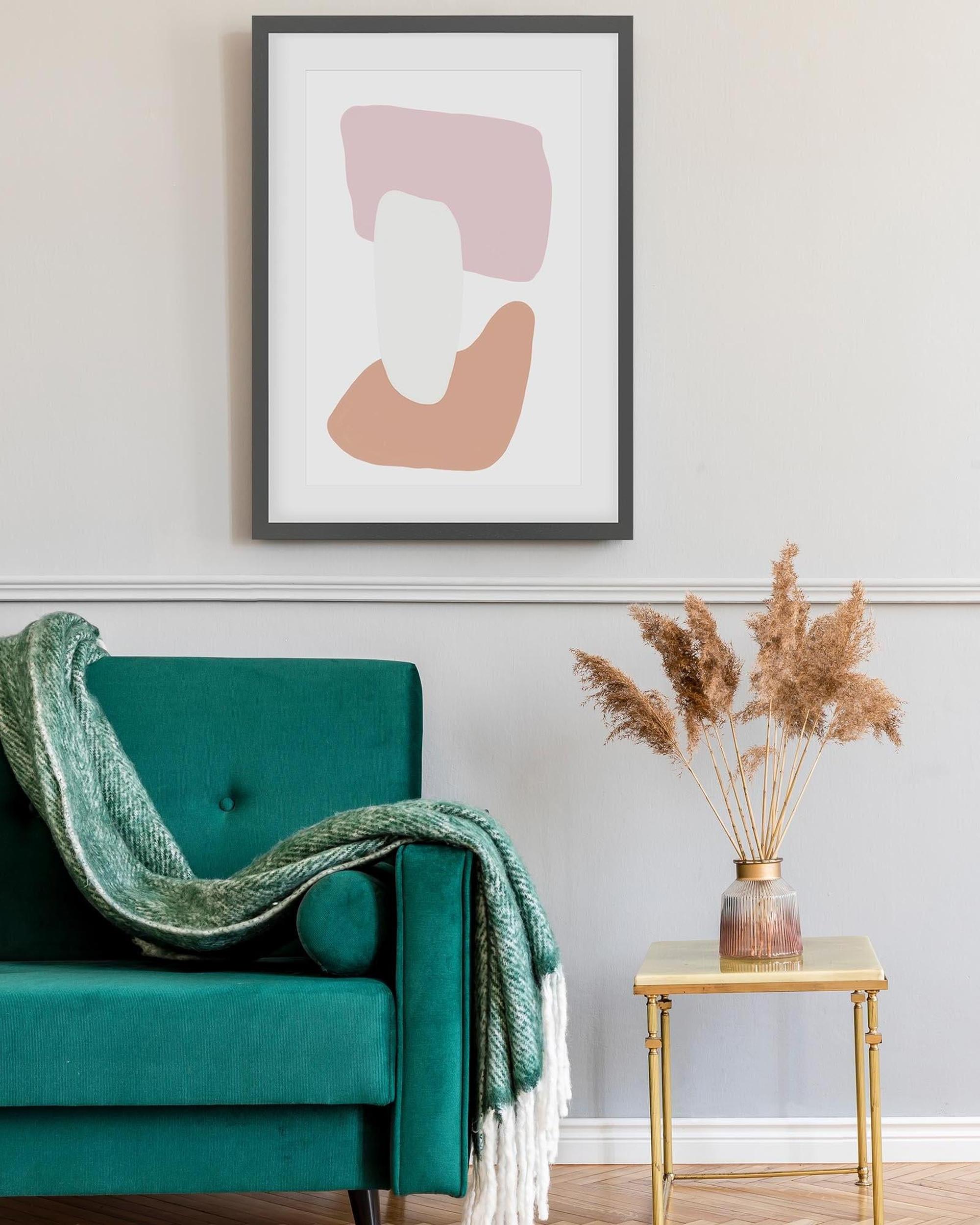 Teal armchair with a green blanket, gold side table with dried plants, and abstract art on the wall.