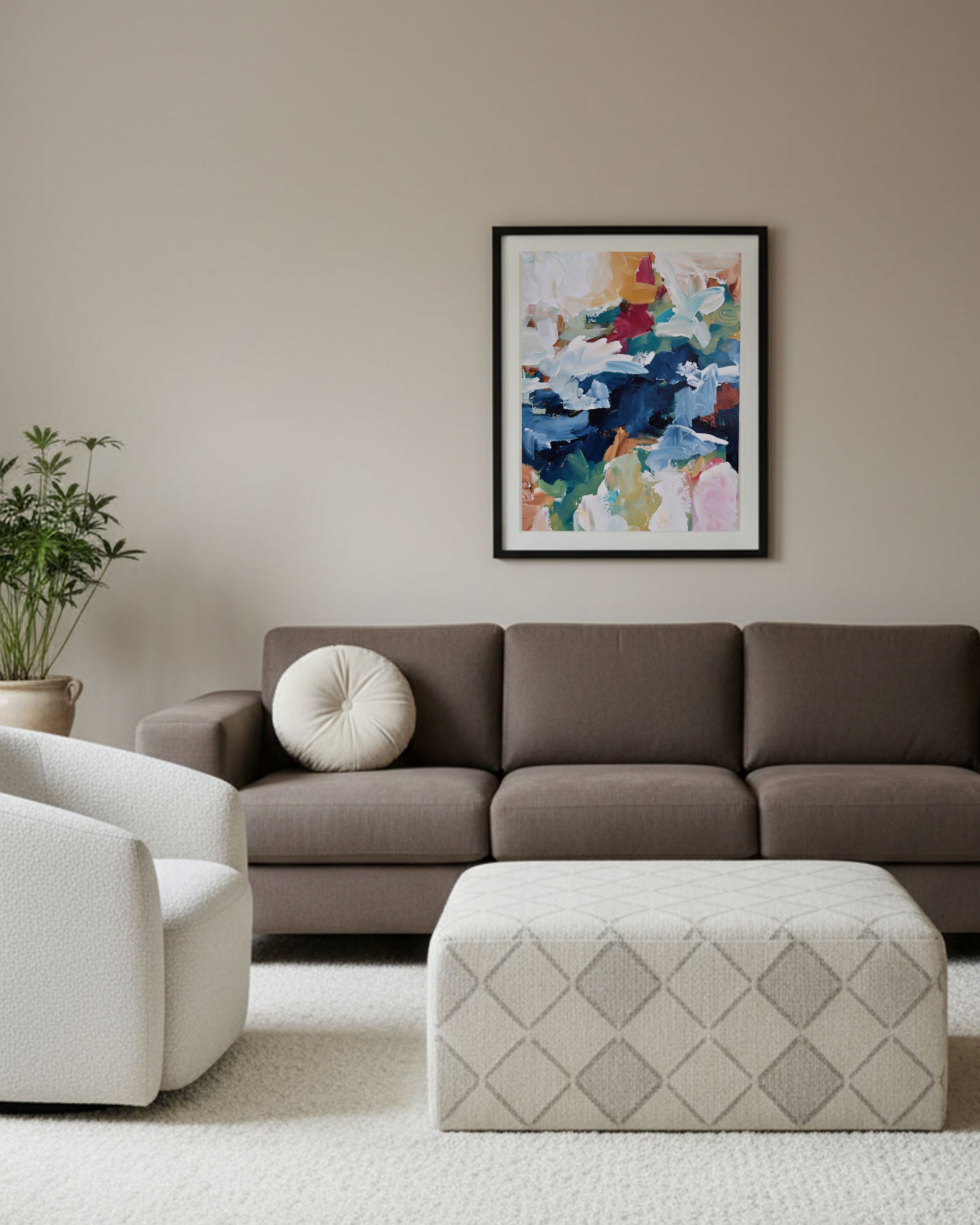 Living room with a brown sofa, white armchair, and a colorful abstract painting on the wall.