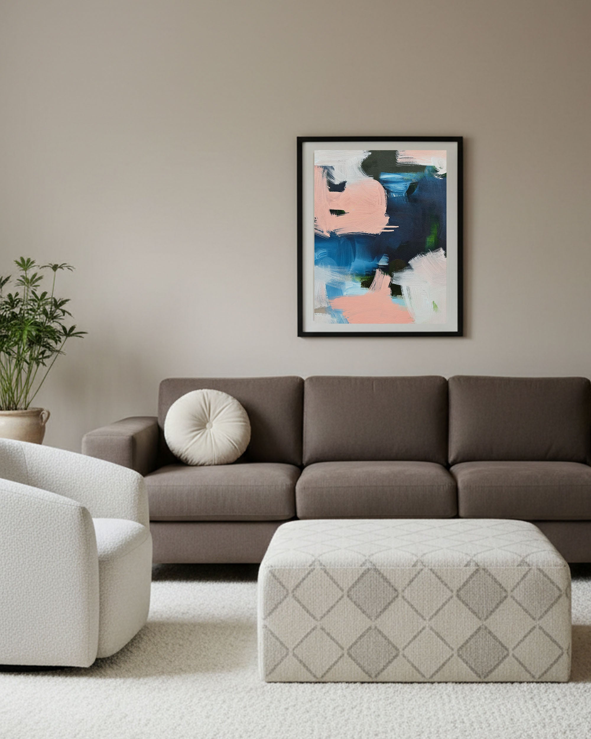modern Japandi living room with large modern navy blue and pink abstract wall art, brown scandinavian sofa with accent cream chair and bespoke ottoman.