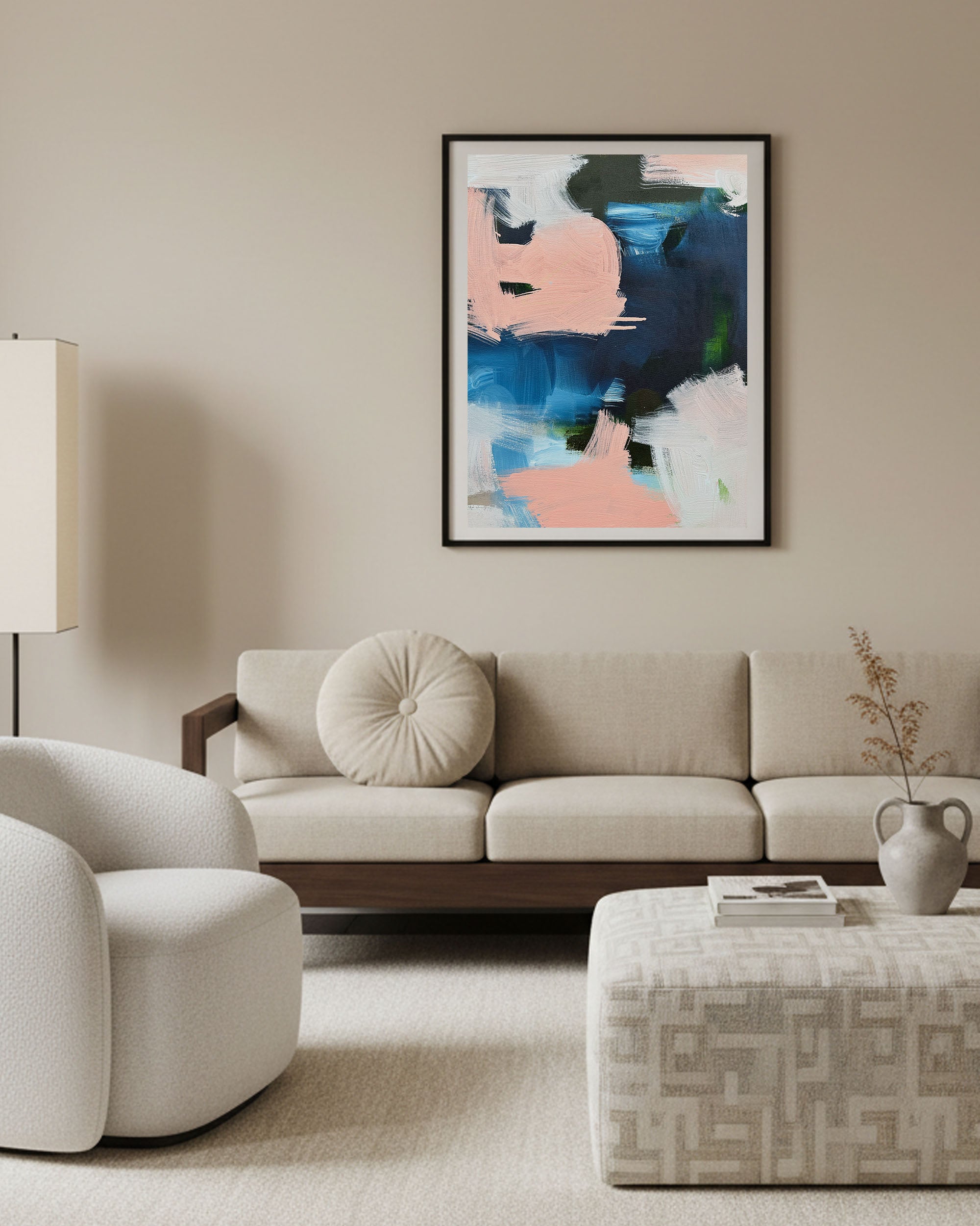 Modern living room with a beige sofa, armchair, and abstract painting on the wall.