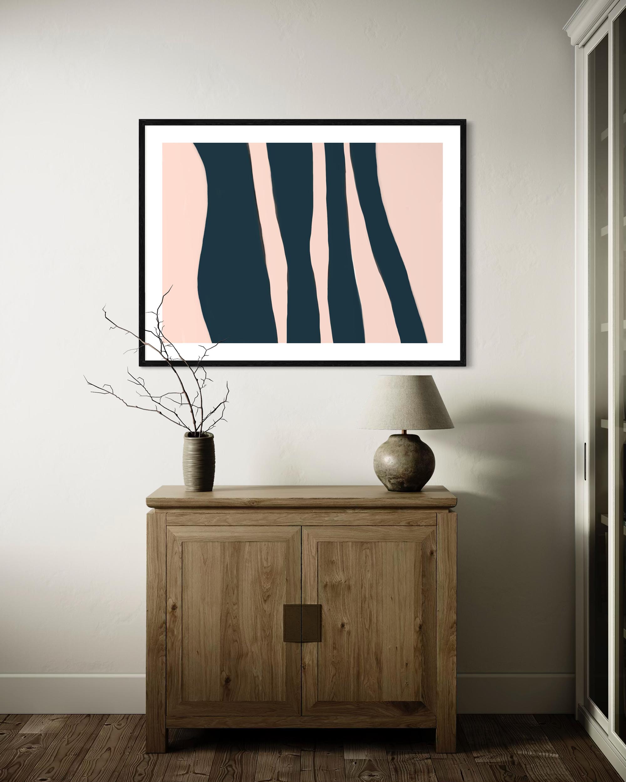 Framed abstract art on a wall above a wooden cabinet.