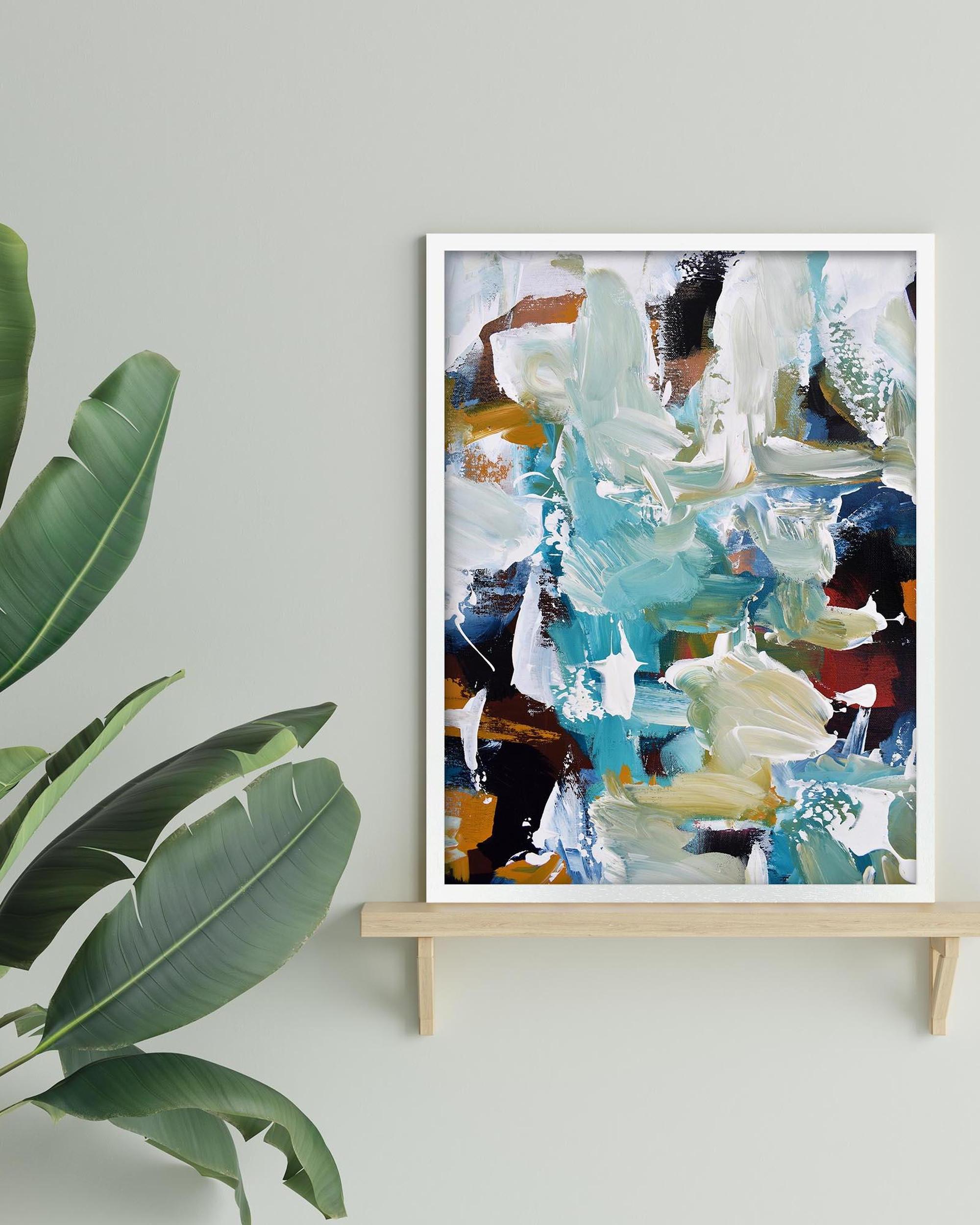 Abstract art print on a stand with a plant to the left on a light gray wall