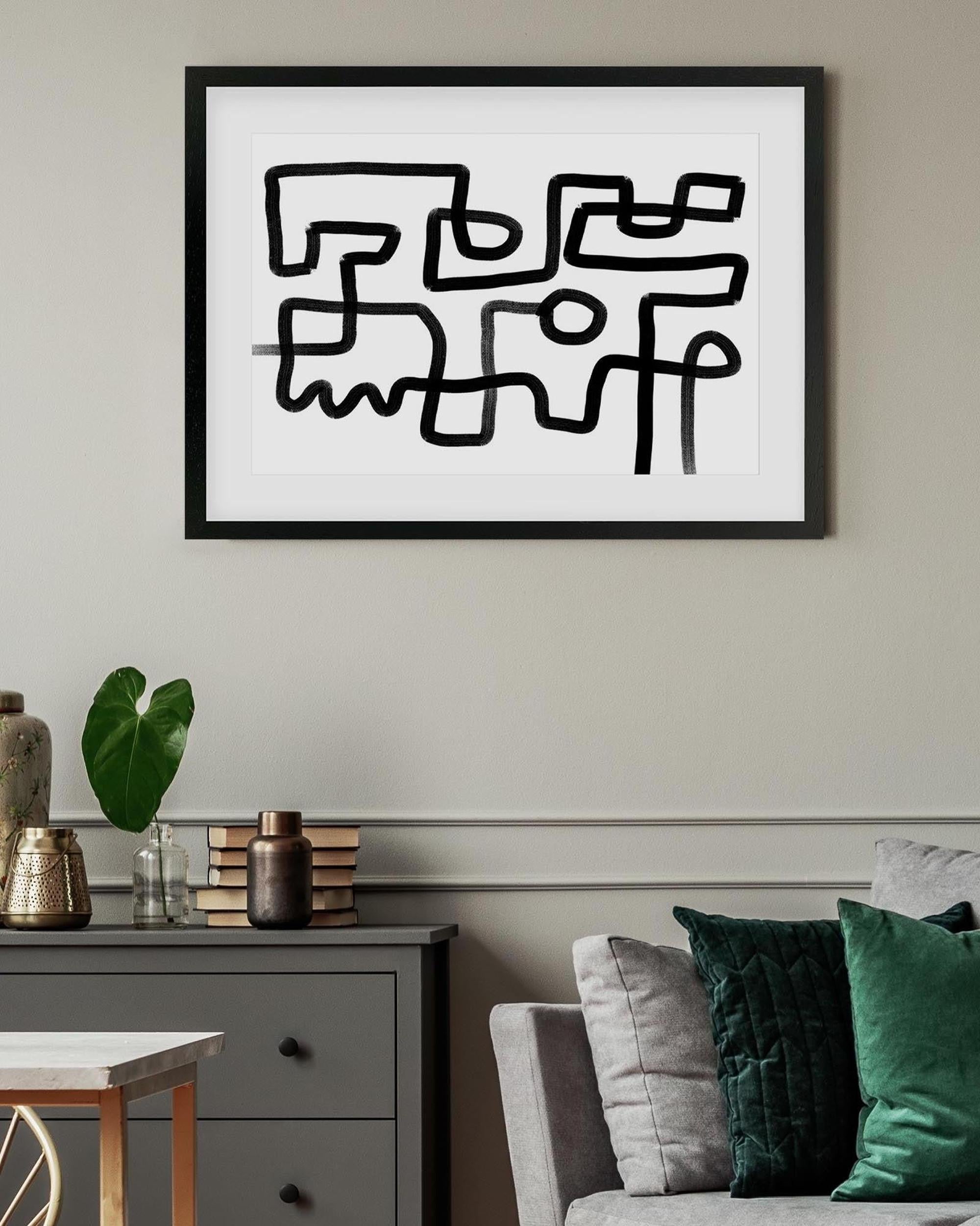 Framed abstract artwork on a wall above a sofa with decorative pillows.