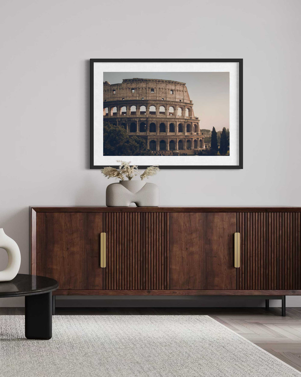 Framed picture of the Colosseum above a wooden sideboard in a room.
