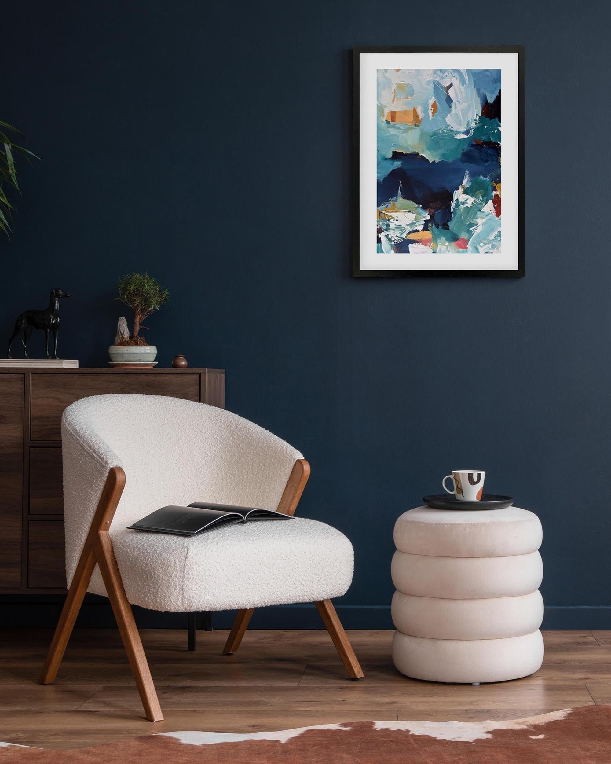 Modern living room with a white armchair, side table, and abstract art on the wall.