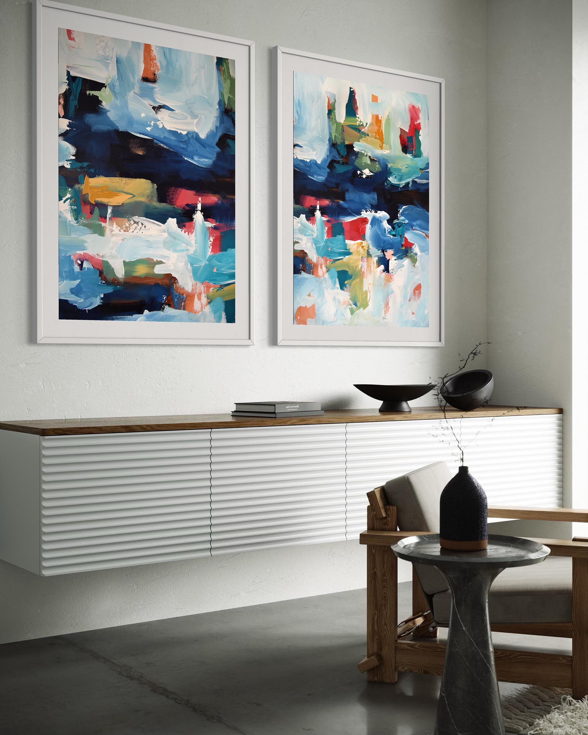 Two abstract paintings on a wall above a console table in a living room.