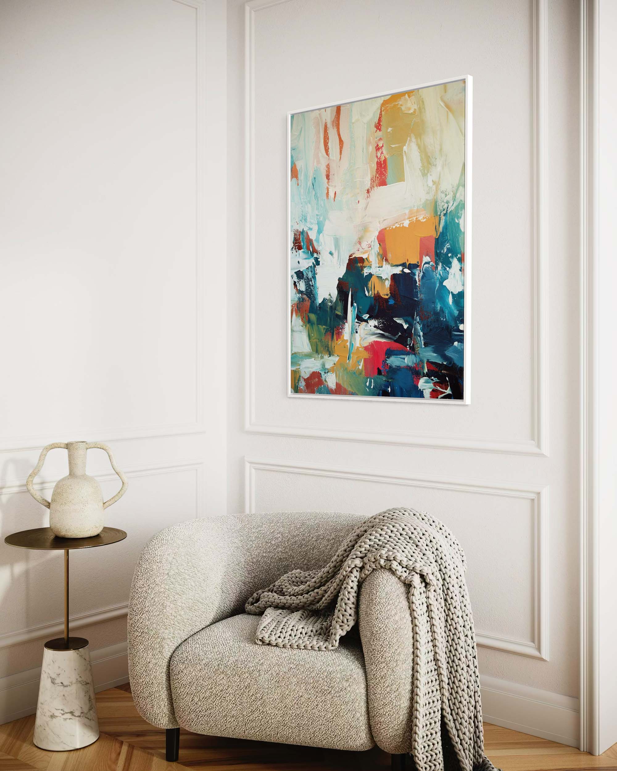 Modern living room with a colorful abstract painting on the wall, a beige armchair with a blanket, and a small side table.