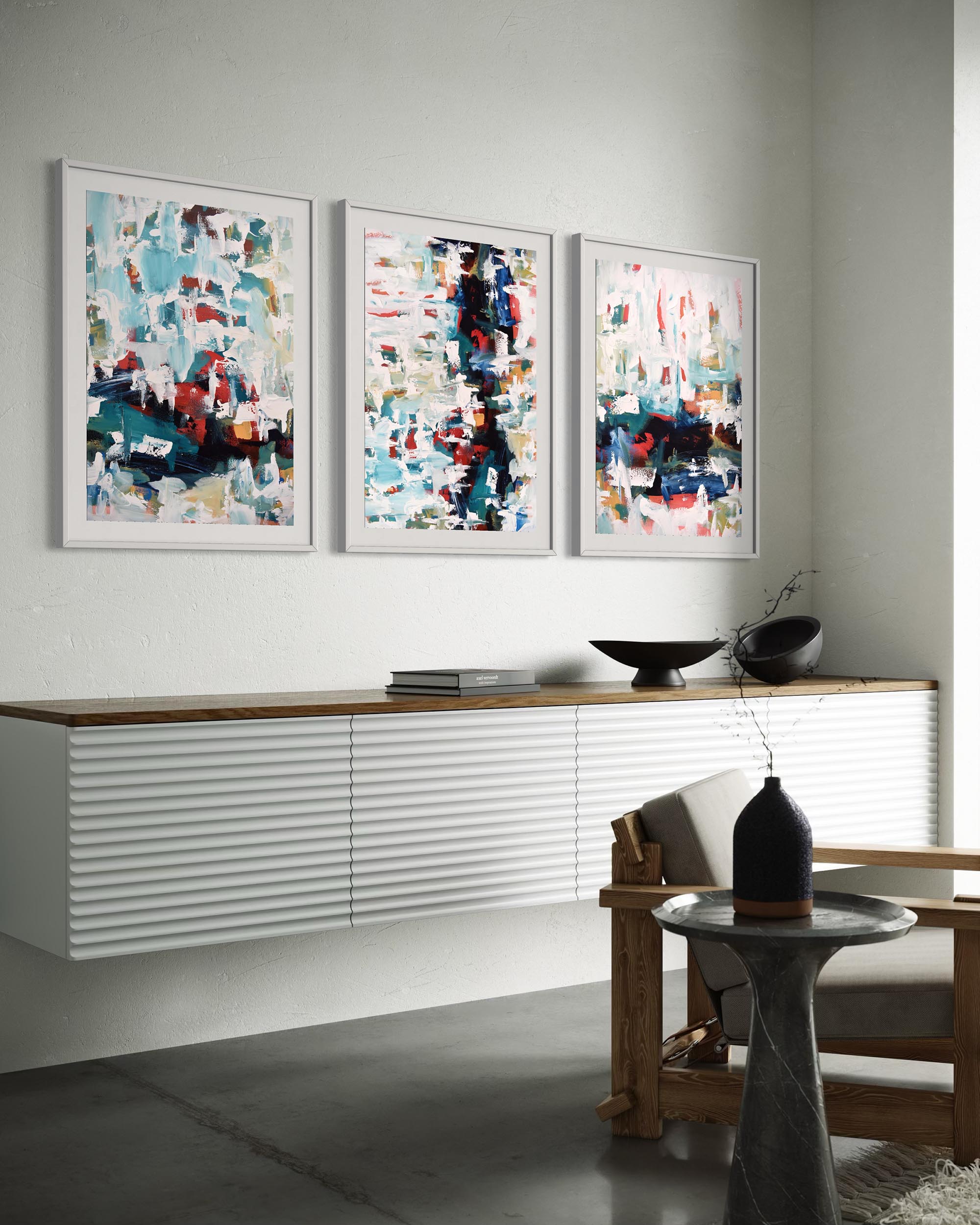 Three abstract paintings on a wall above a console table in a modern living room.