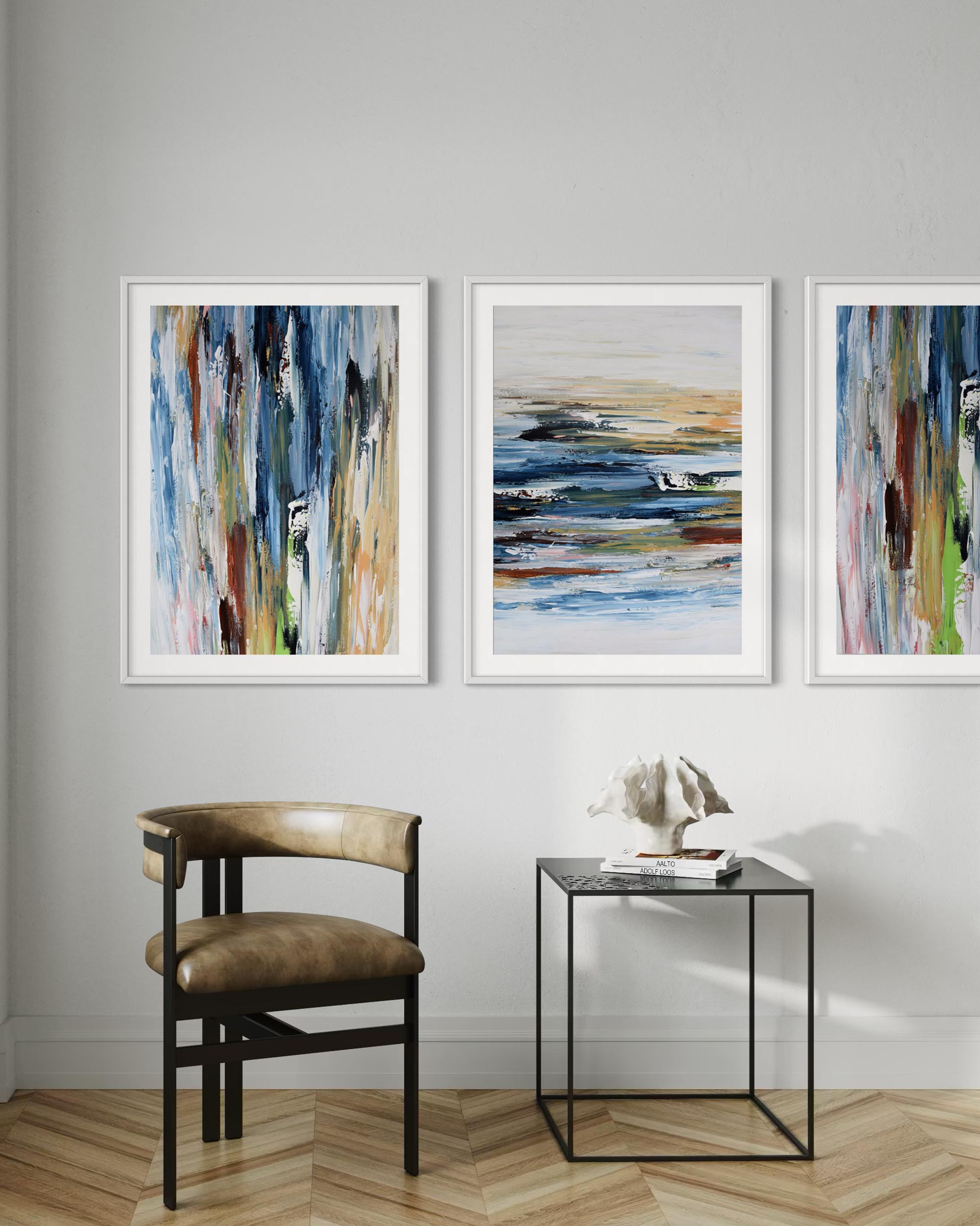 Three abstract paintings on a wall with a chair and small table below.
